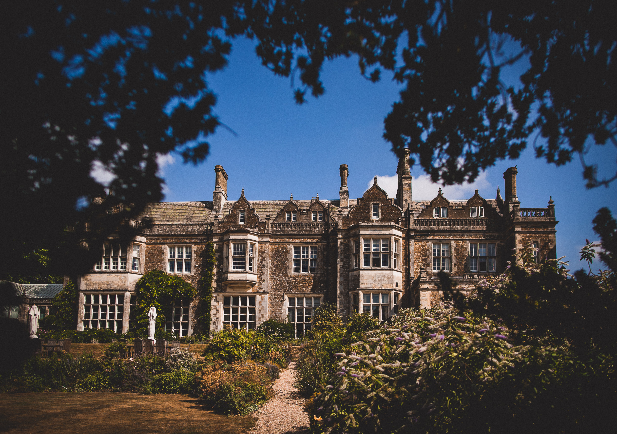 A picturesque wedding venue featuring a grand mansion enveloped by lush trees, ideal for capturing unforgettable moments as a wedding photographer to the groom.