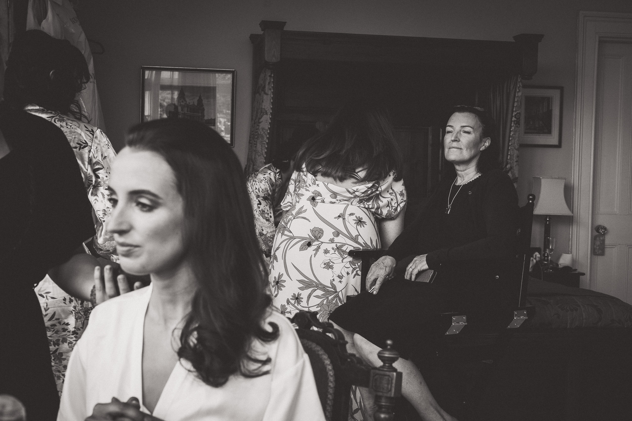 A black and white photo of a bride getting ready in a room, captured by a wedding photographer.