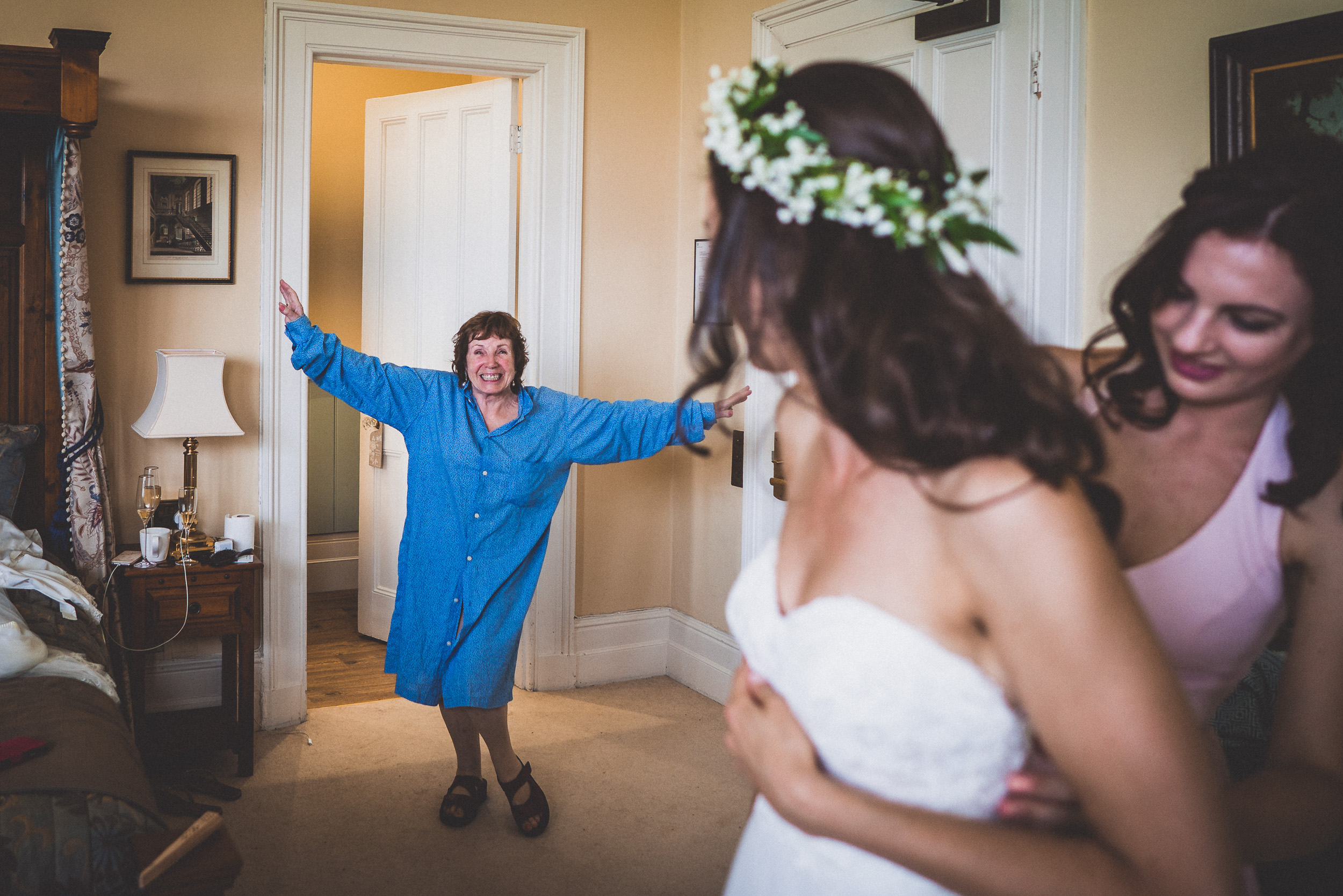 A wedding photographer captures a bride and her bridesmaids preparing in a room.