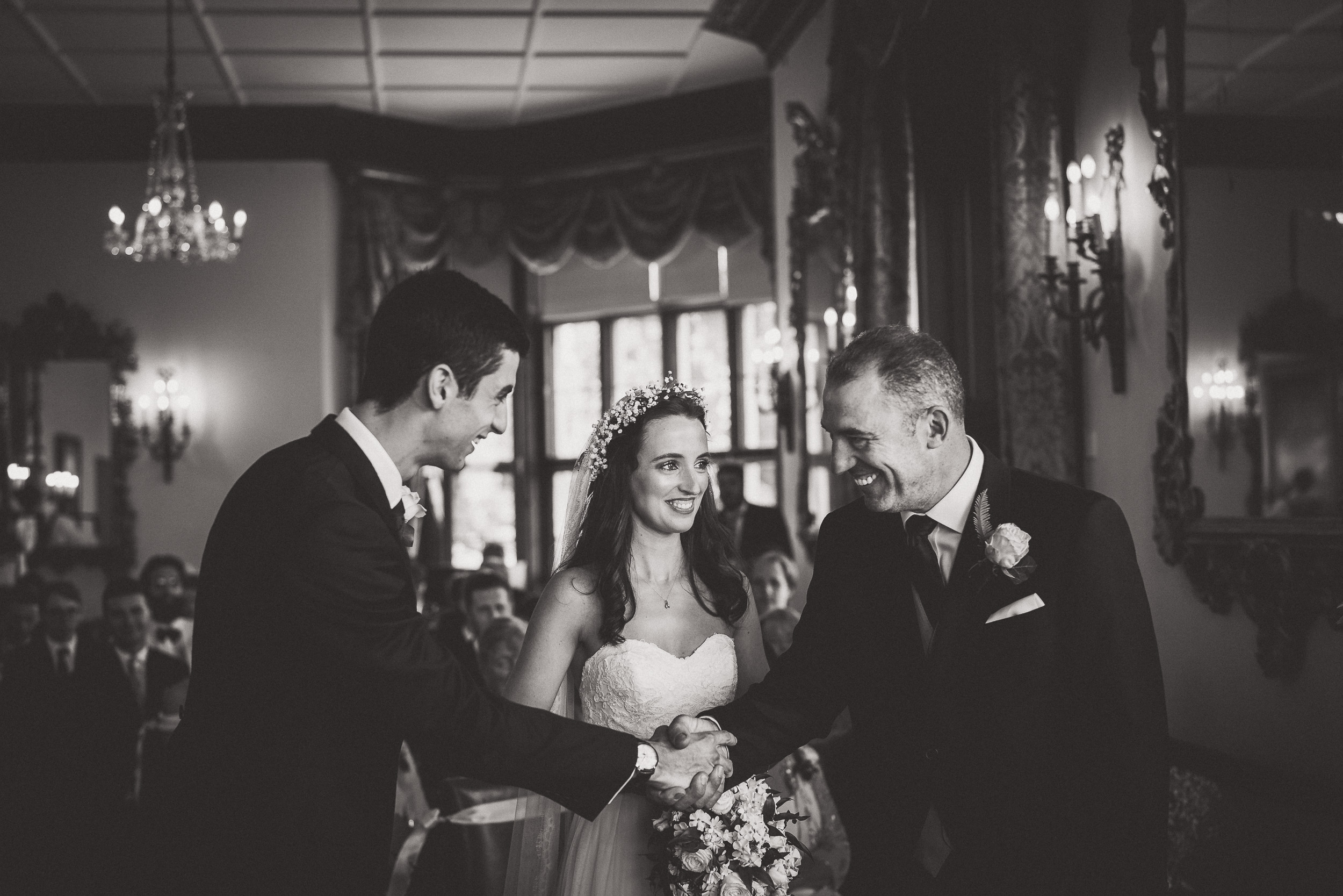 Black and white wedding photo of bride and groom shaking hands.