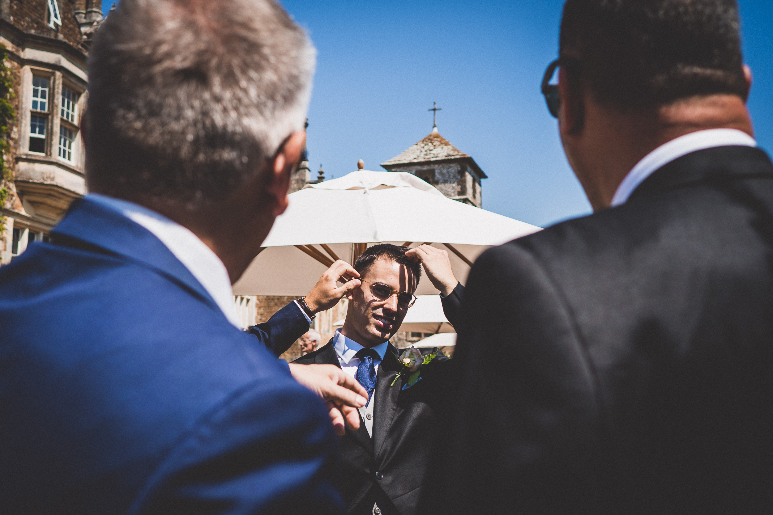 A man in a suit is putting on his tie for a wedding ceremony.