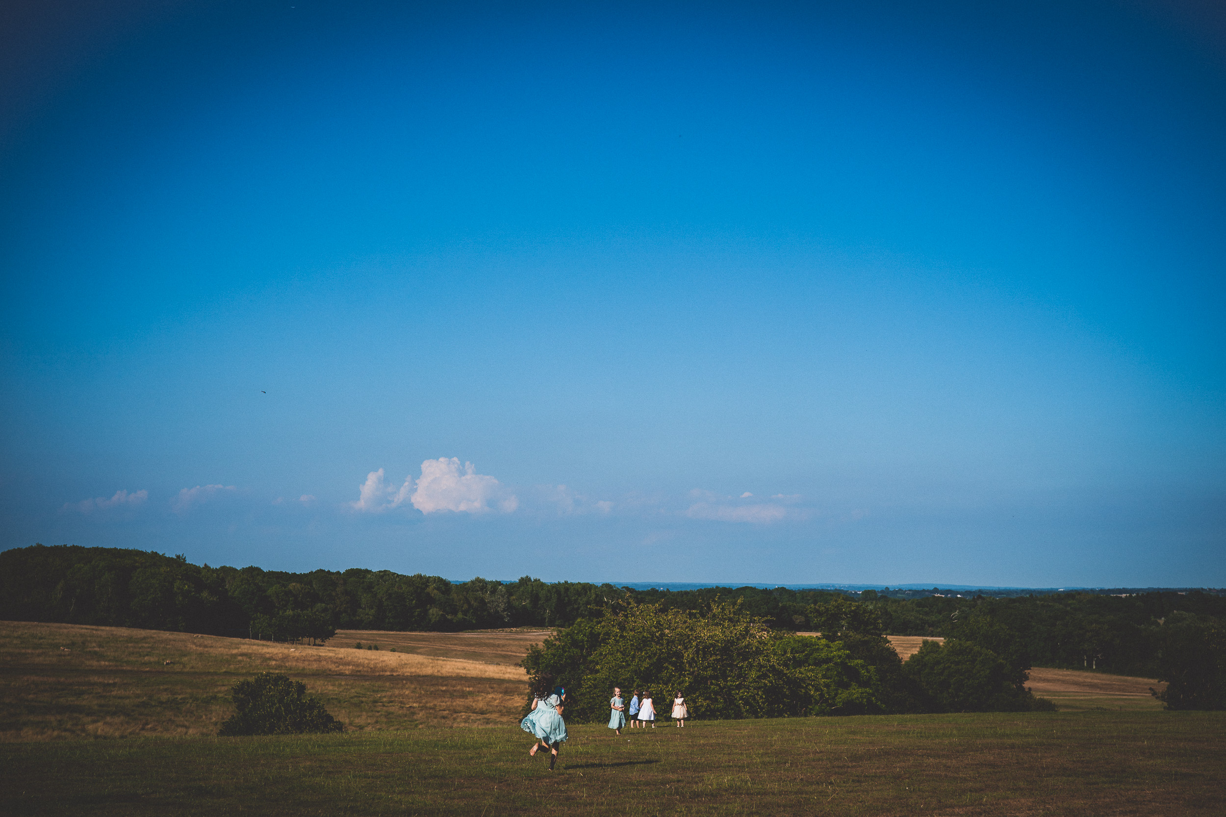 A bride and groom posing for their wedding photo in a field with a blue sky.