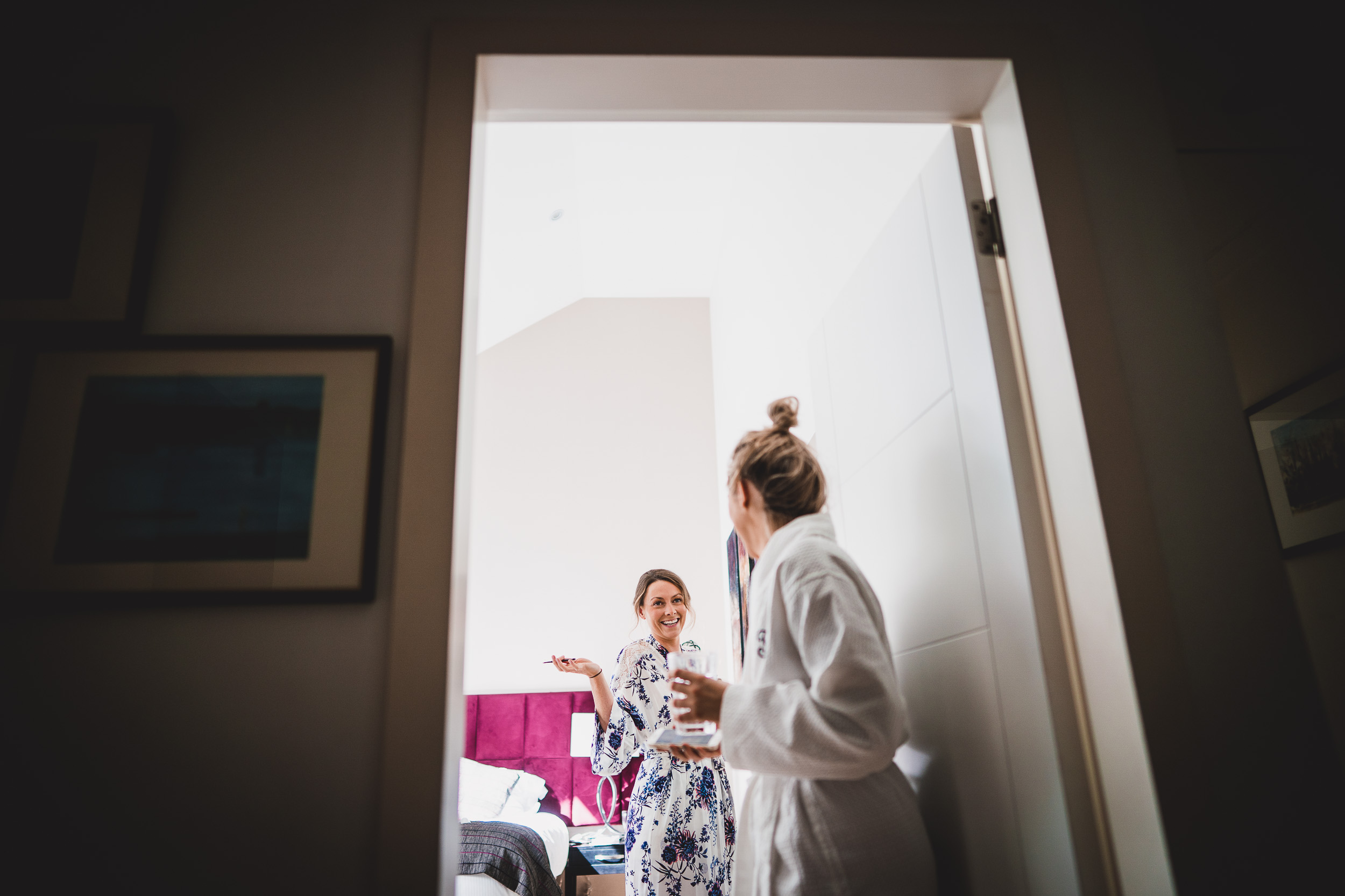 Two wedding photographers capturing two women in robes standing in front of a door.