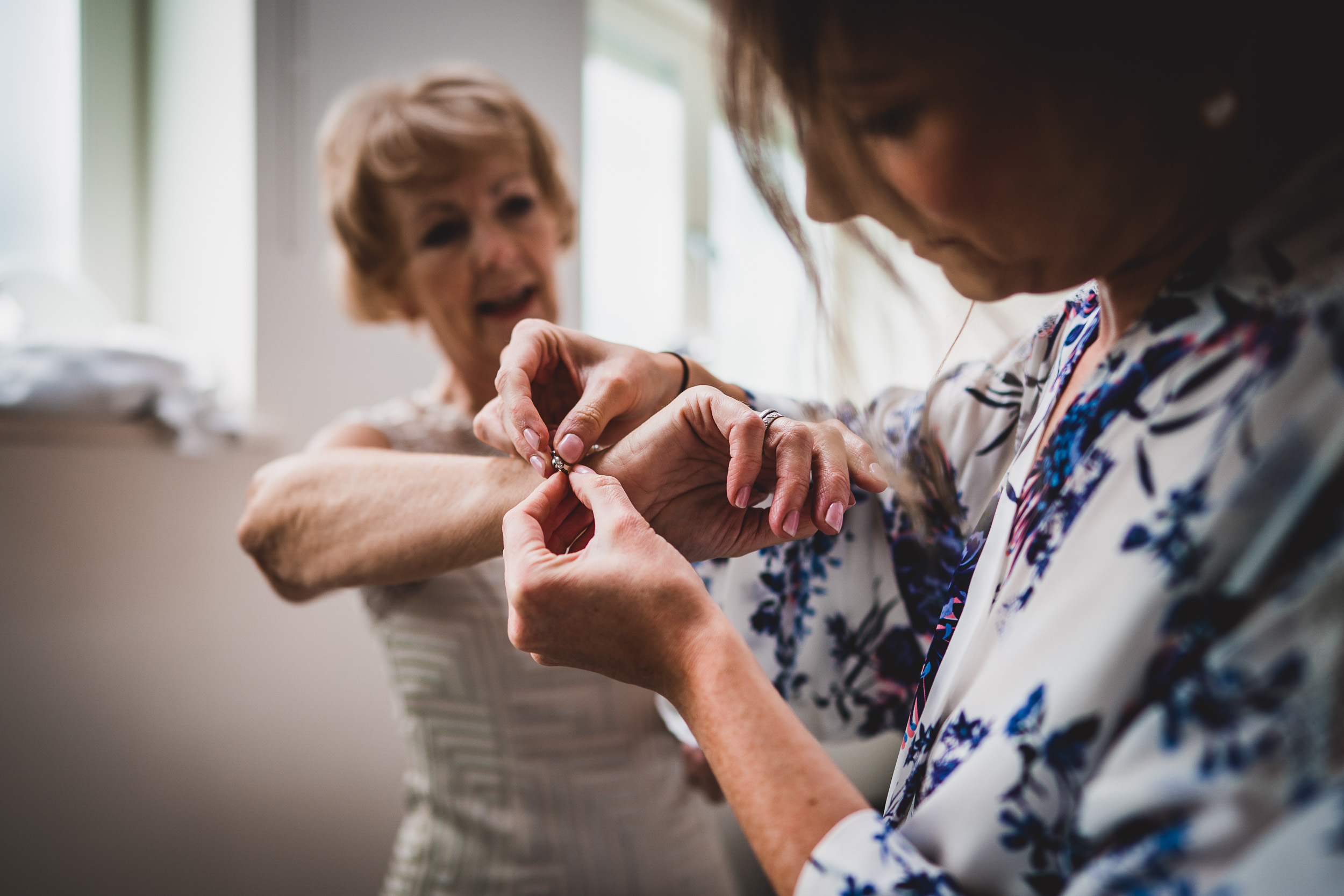 A bride assisting her mother with her wedding ring.