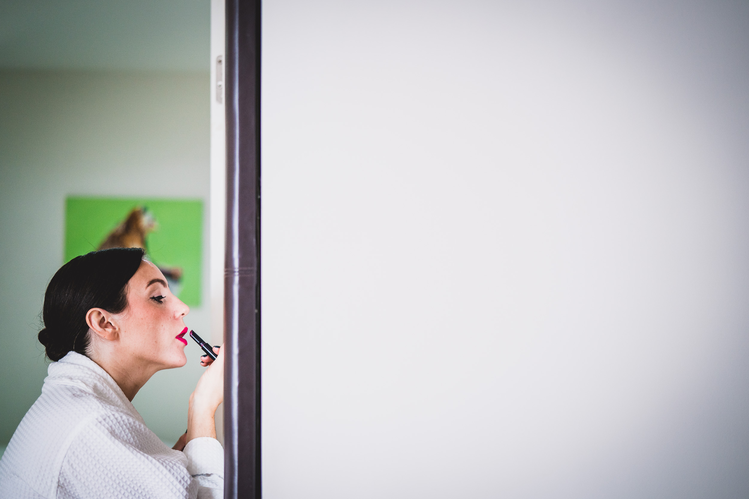 A bride-to-be is groomed by a wedding photographer while standing in front of a door.