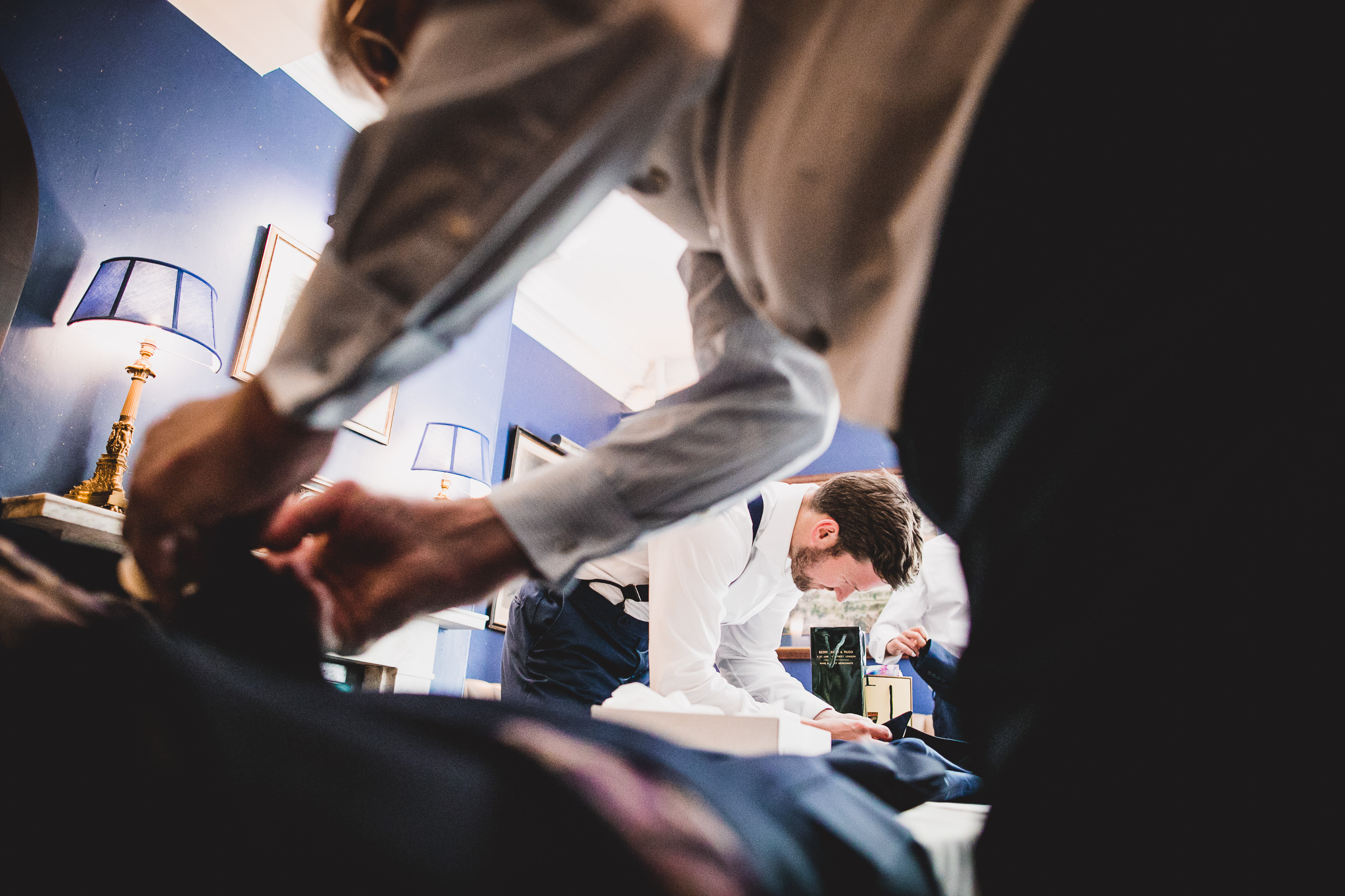 Groomsmen in a room, preparing for the wedding, while putting on ties.