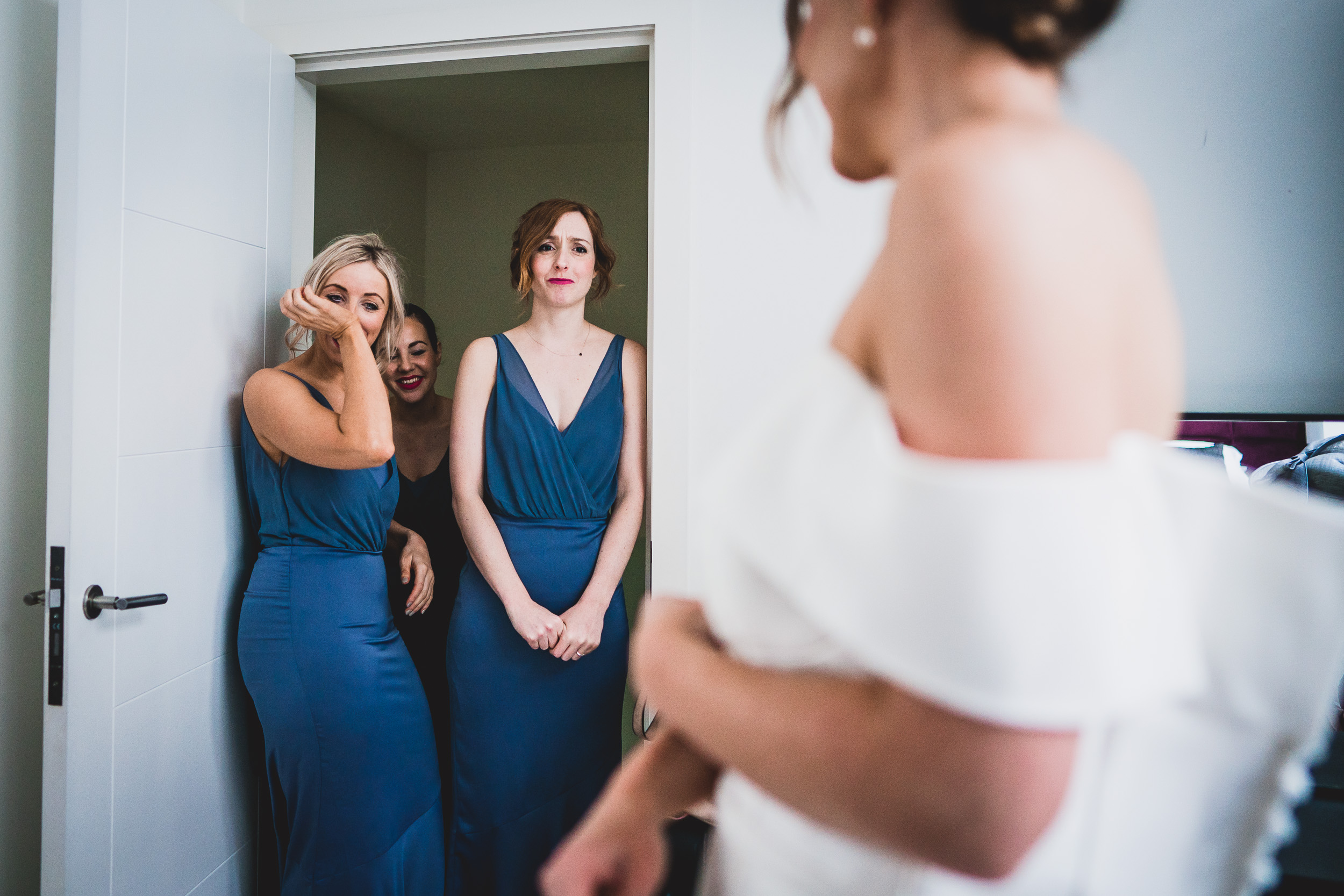 Bride and bridesmaids admiring each other in a wedding photo.