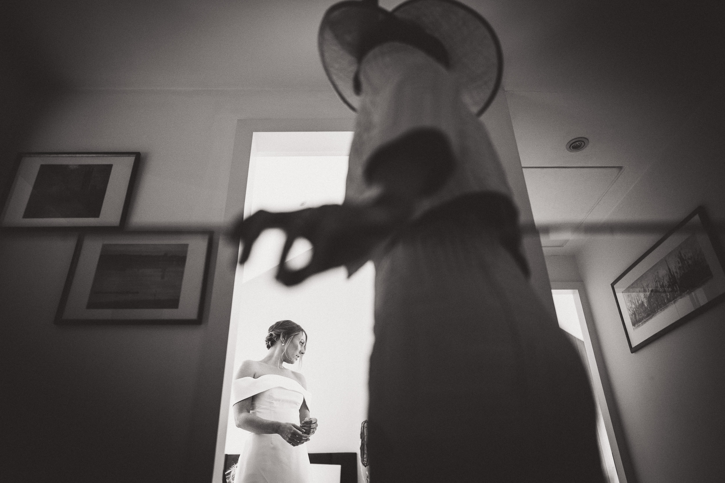 A bride and groom in wedding attire posing for their wedding photographer in front of a mirror.