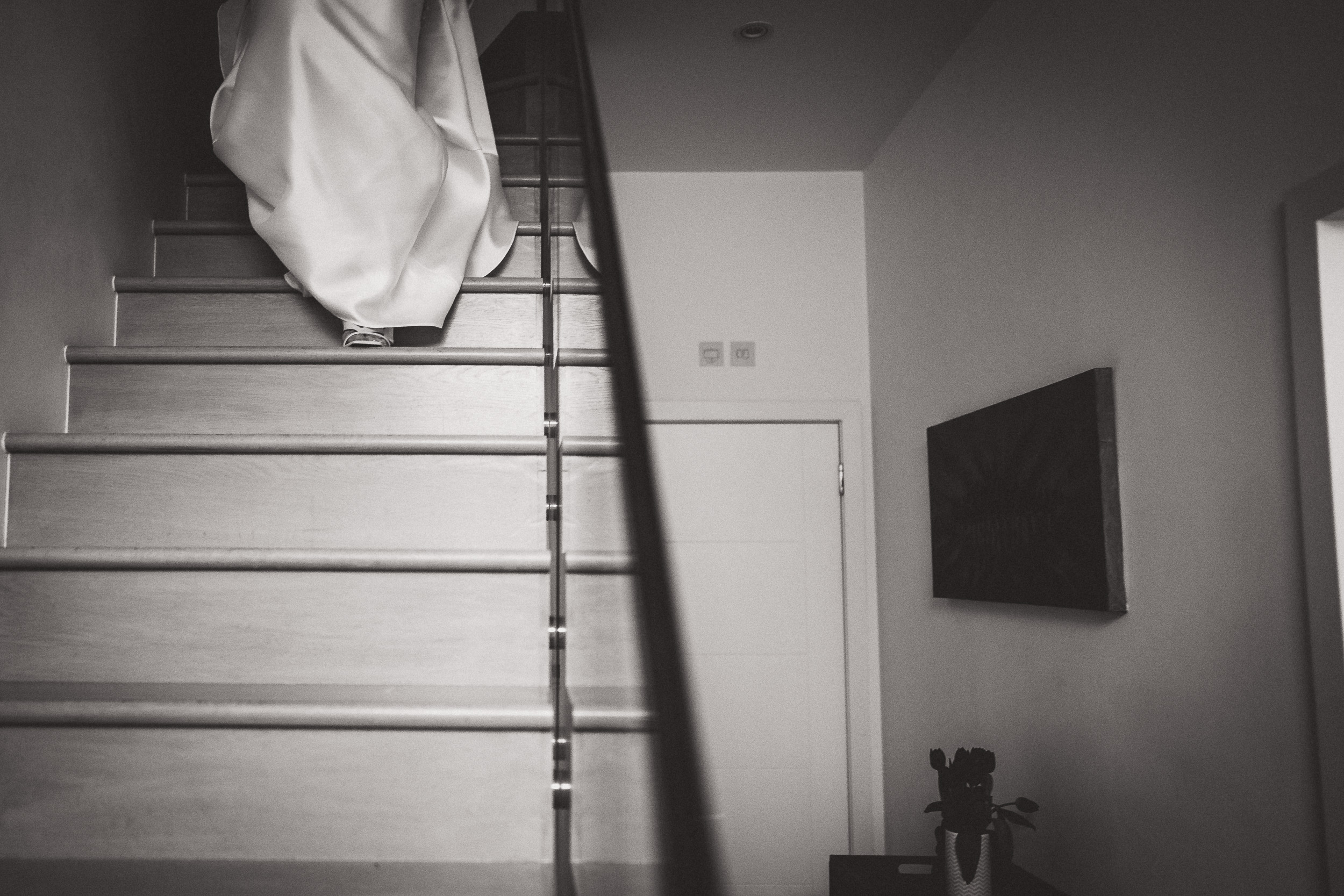 A bride is descending the stairs, radiantly adorned in her wedding dress as captured by the wedding photographer.