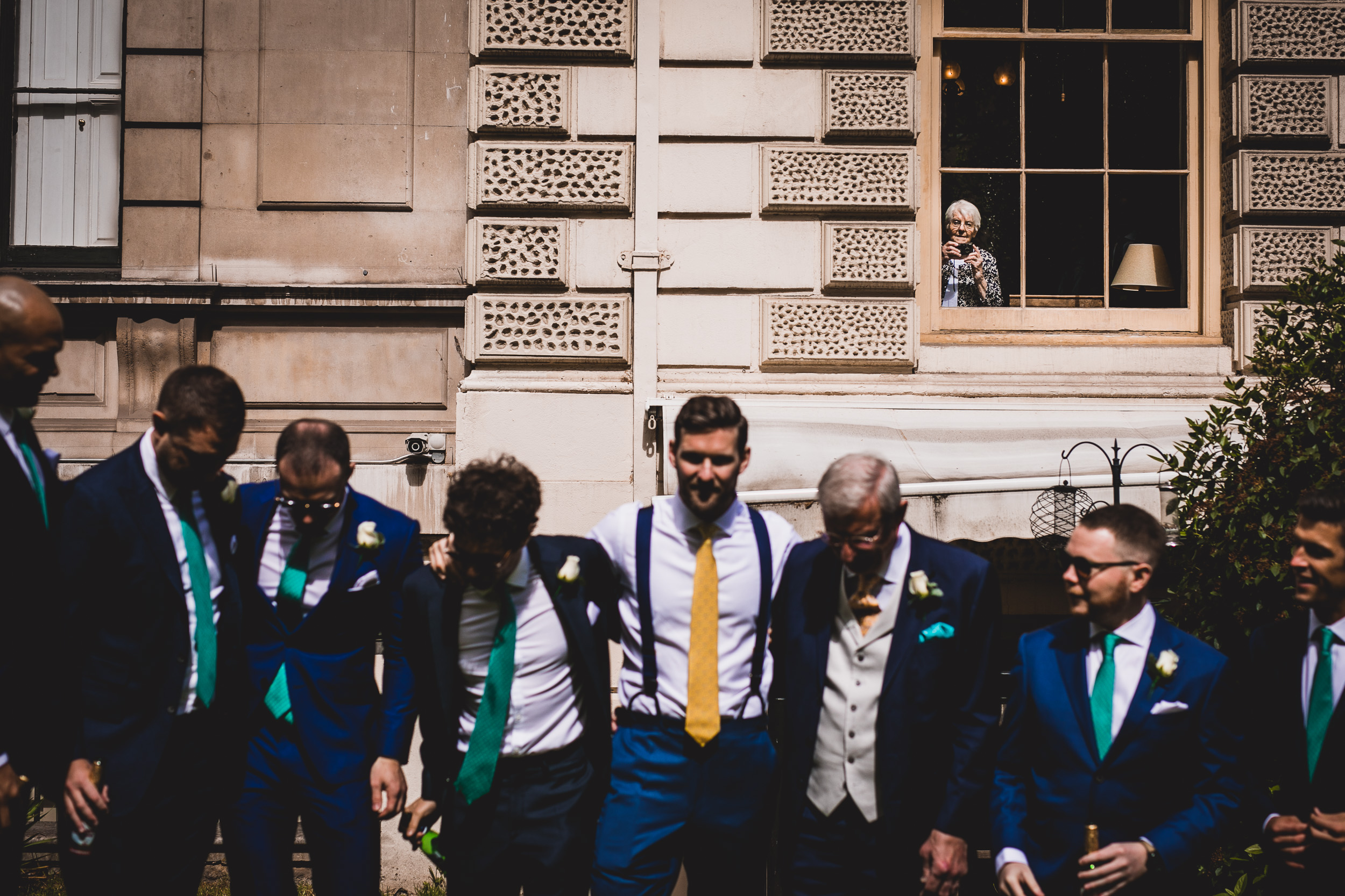 A group of groomsmen posing for a wedding photo in front of a building.