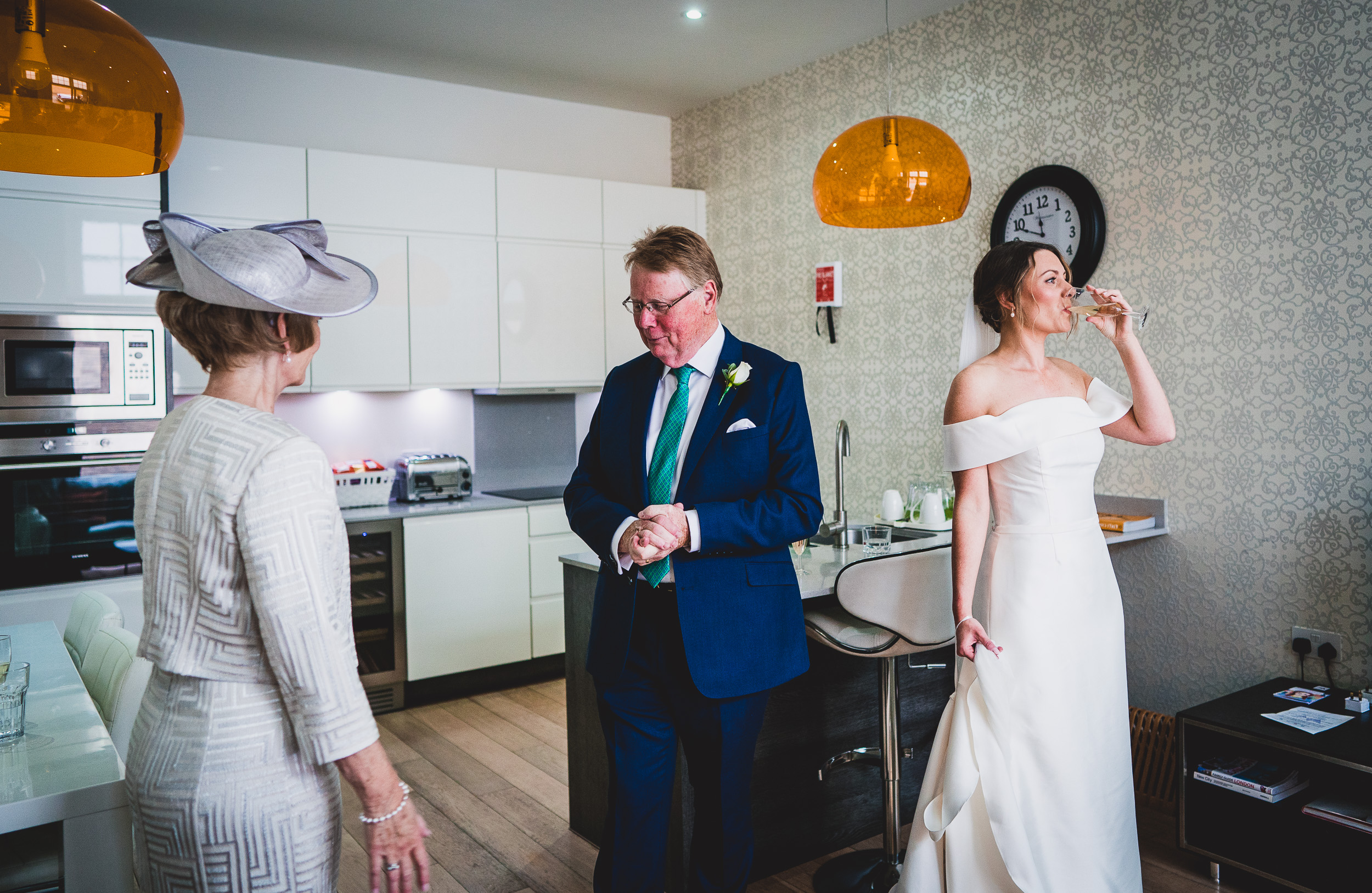 A wedding photographer captures a bride and groom in a kitchen.