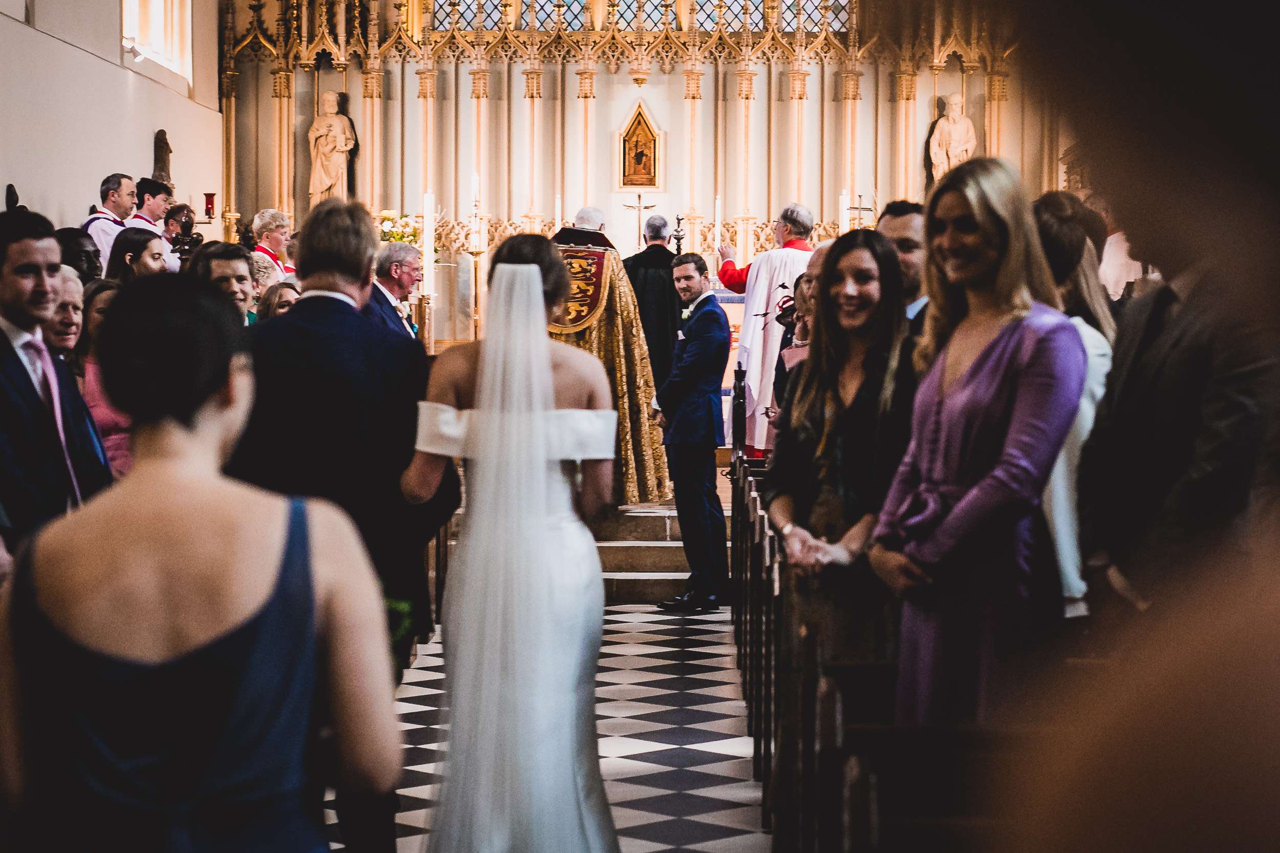 A bride walks down the aisle for her wedding, accompanied by the groom.