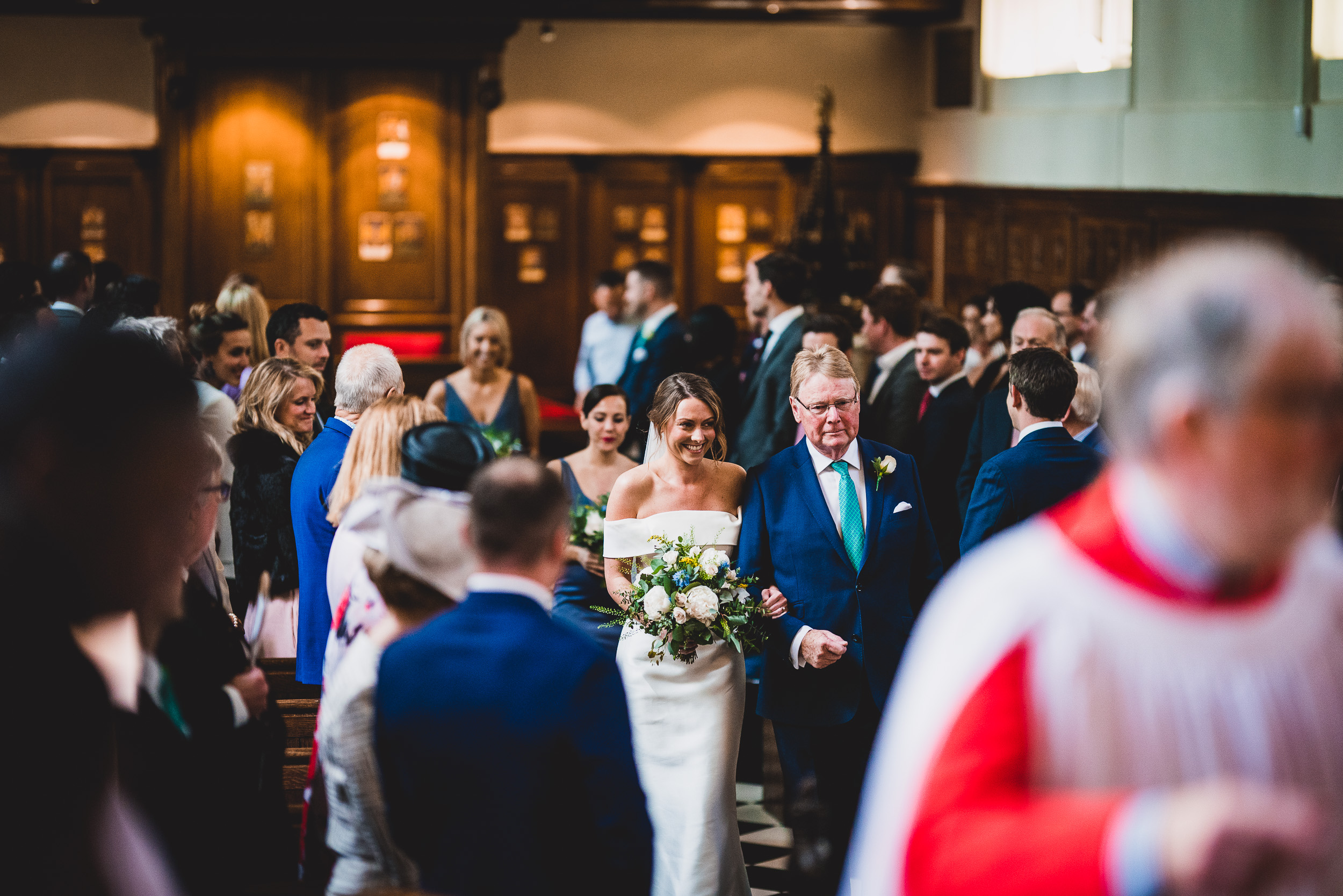 A wedding photographer captures the moment of a bride and groom's walk down the aisle in a church.