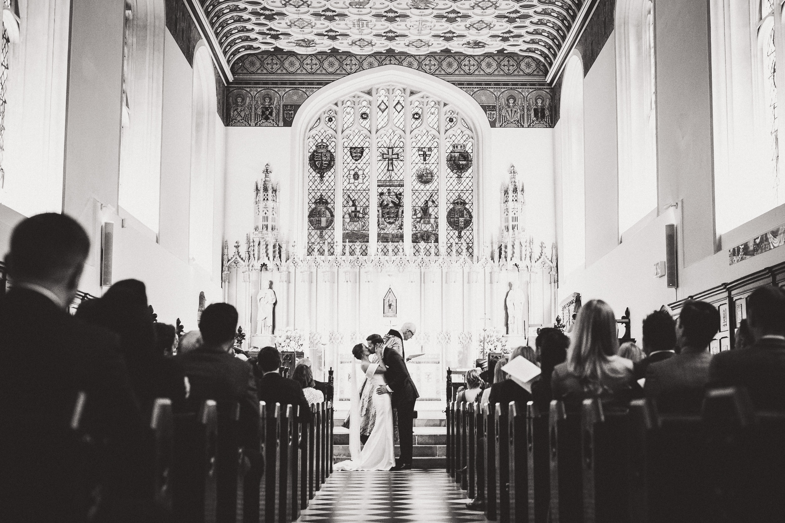 A wedding photo showing a bride and groom kissing in a church.