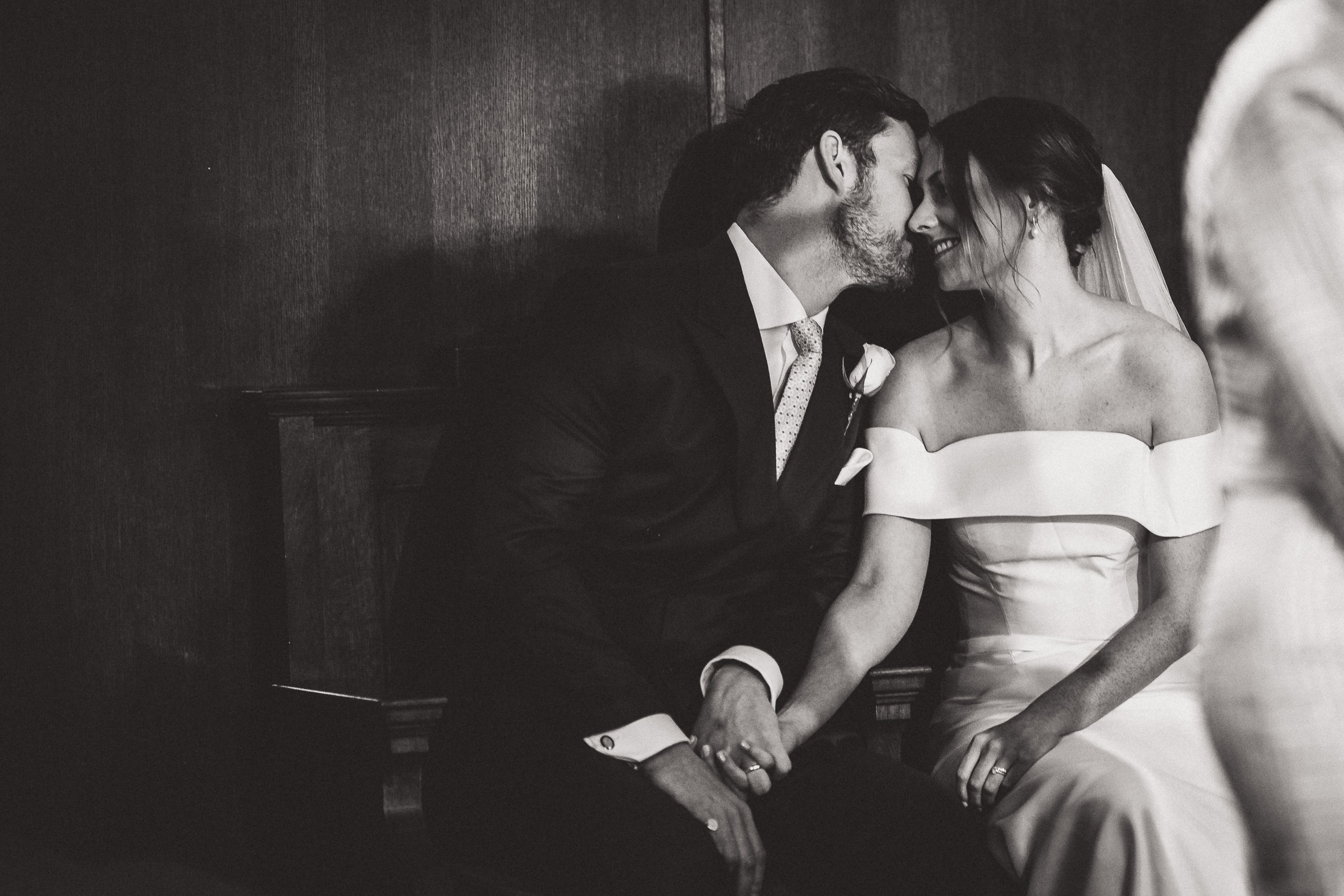 A wedding photo capturing the groom kissing his bride in front of a mirror.