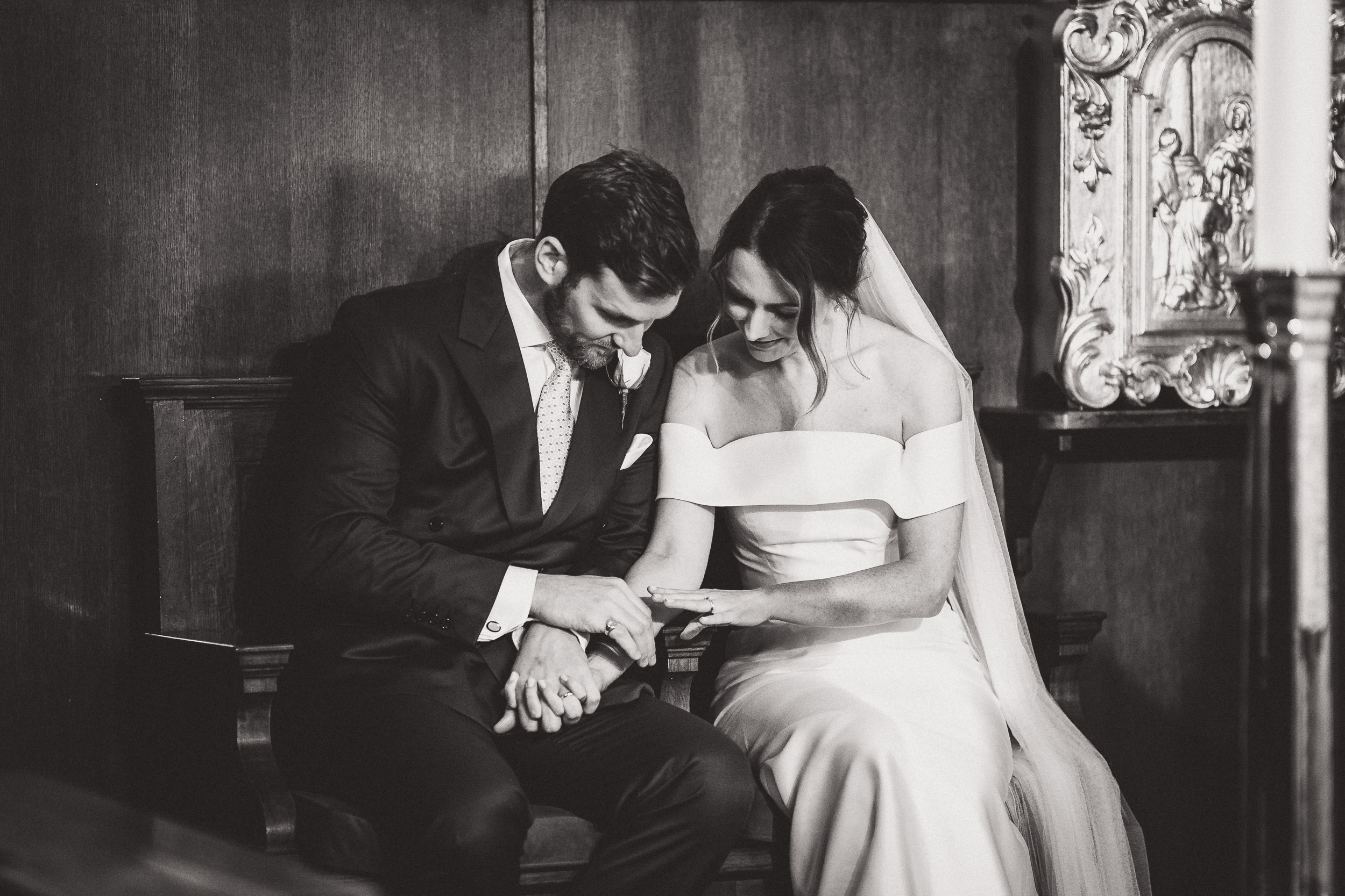 A groom sitting with his bride on a bench during their wedding ceremony.