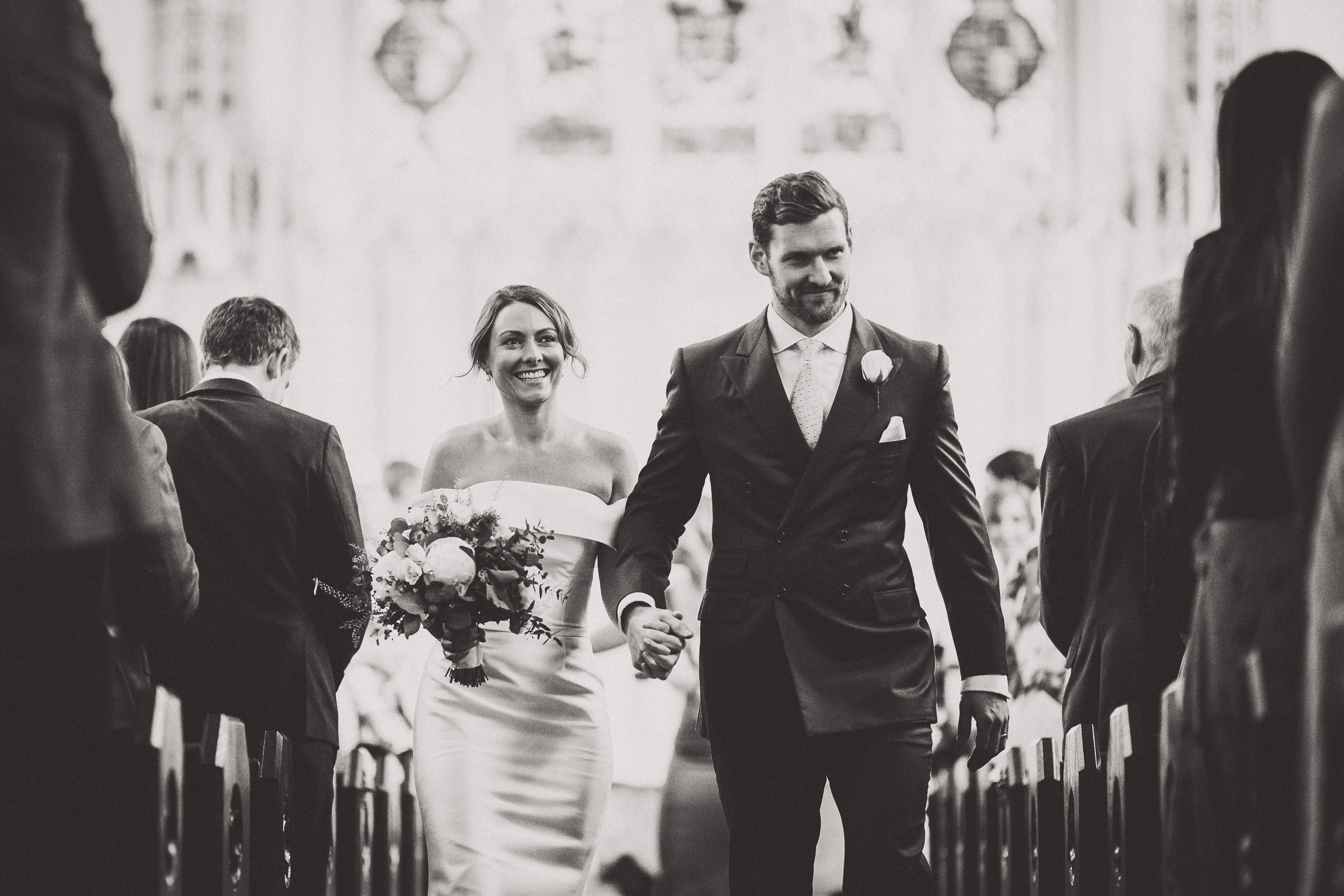 A bride and groom captured by a wedding photographer while walking down the aisle of a church.