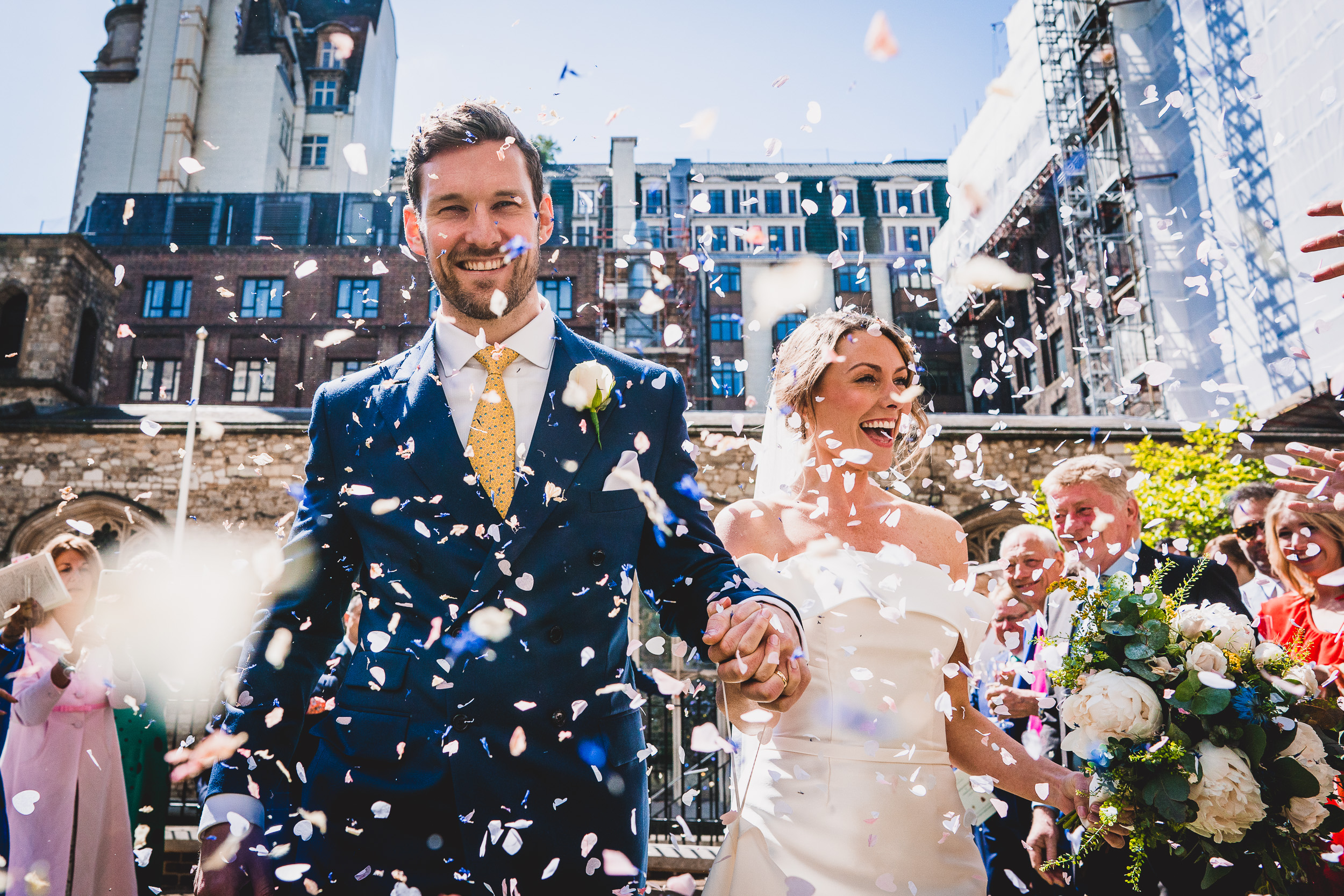 A bride and groom captured in a joyful wedding photograph as confetti rains down around them.