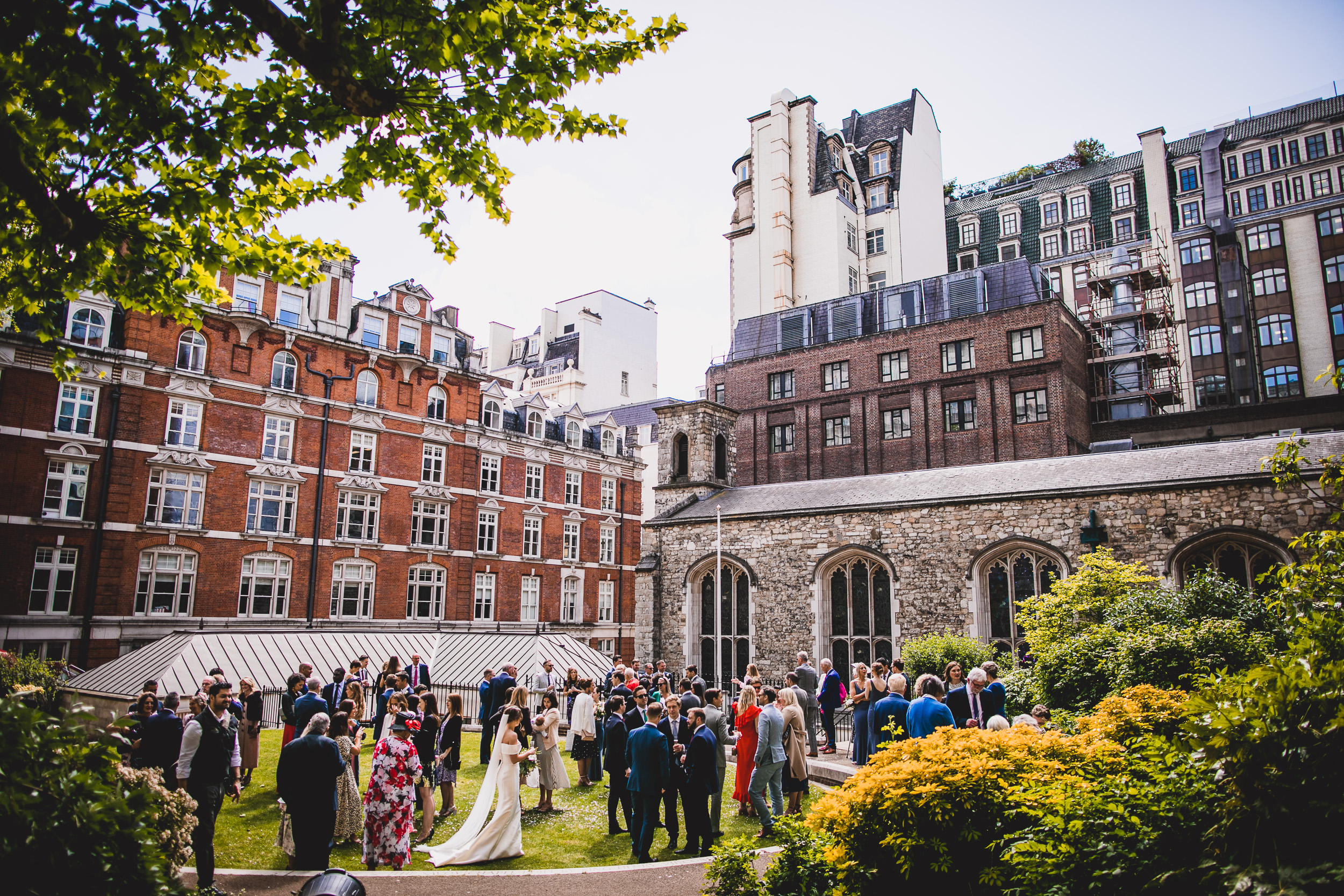 A wedding reception with a groom and wedding photographer in a courtyard in London.