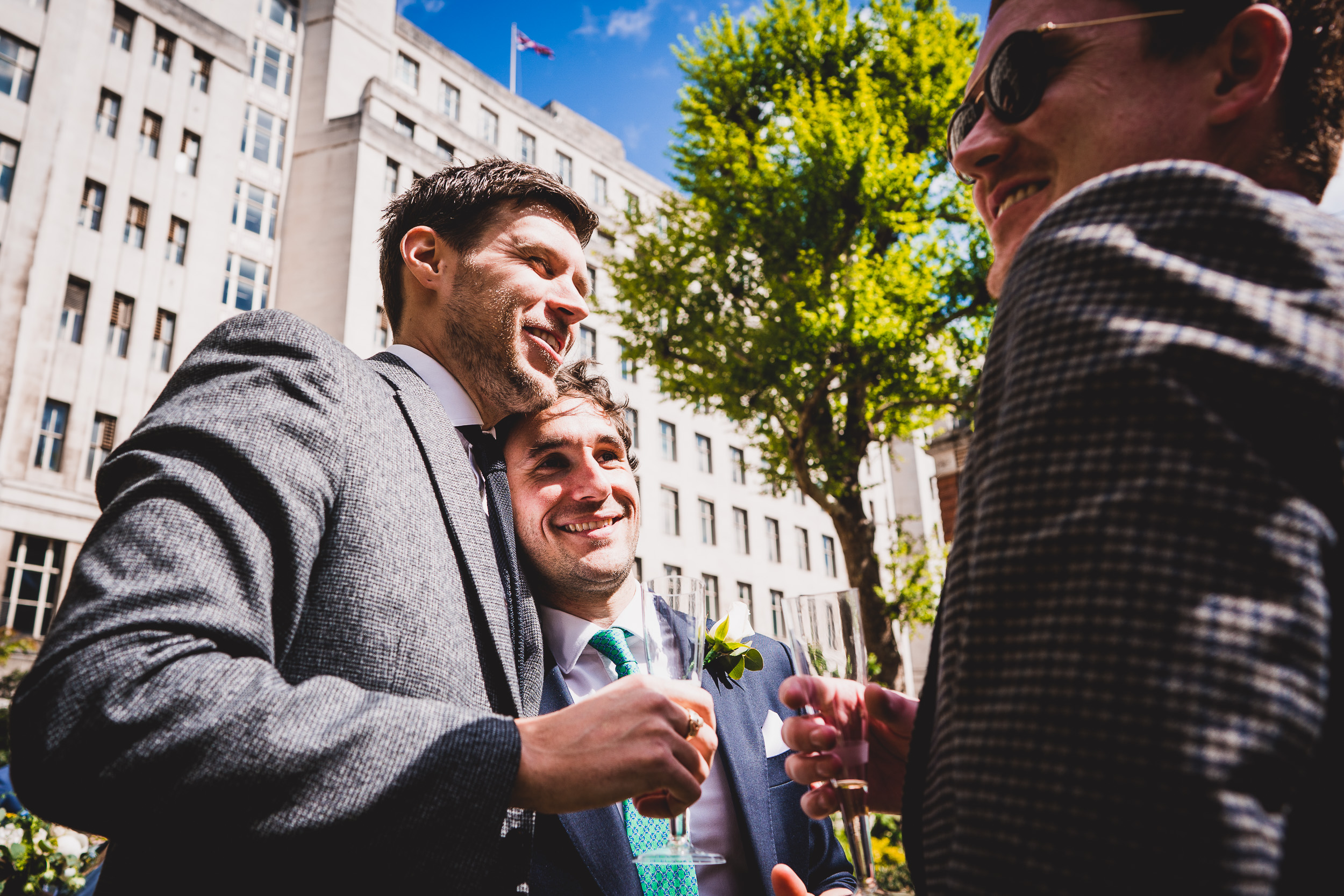 A groom in a suit is laughing with another man.