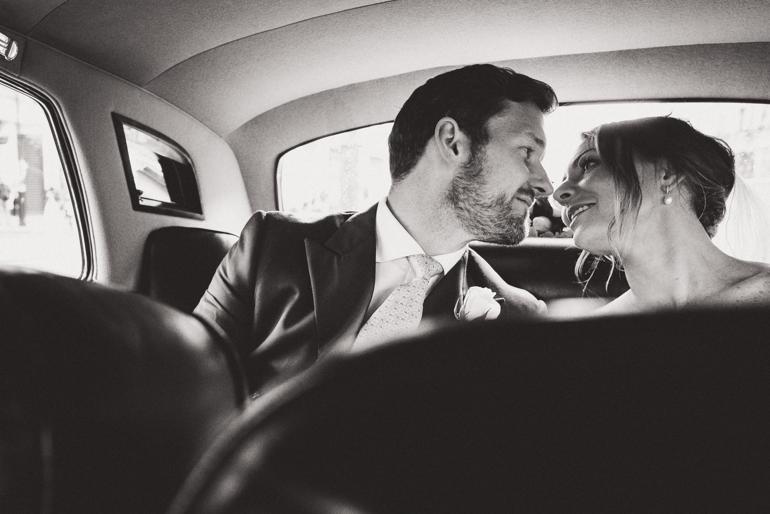 A newly married couple captured in a wedding photo, sharing a kiss inside a limo.