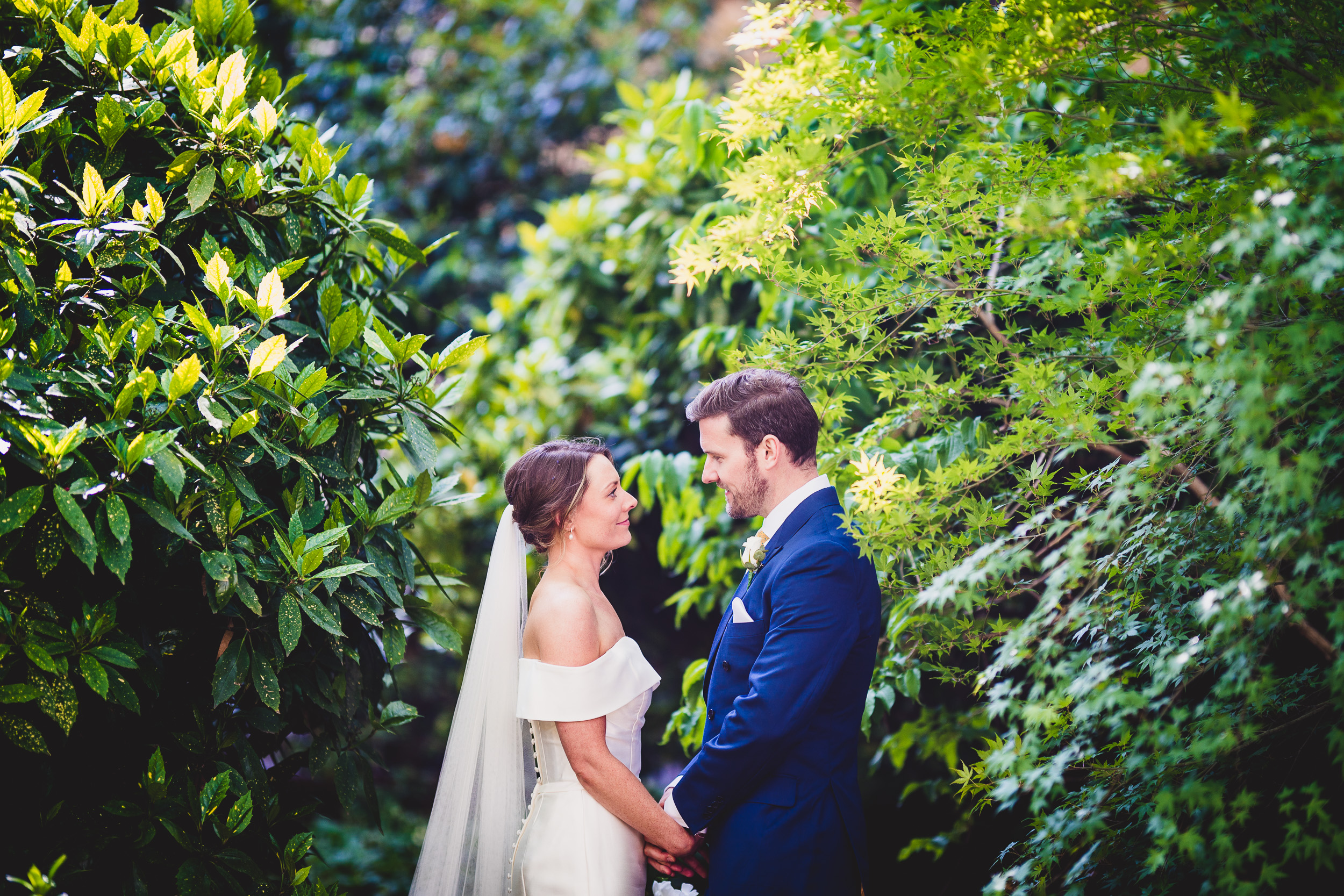 A bride and groom posing for a wedding photo in a garden captured by their wedding photographer.