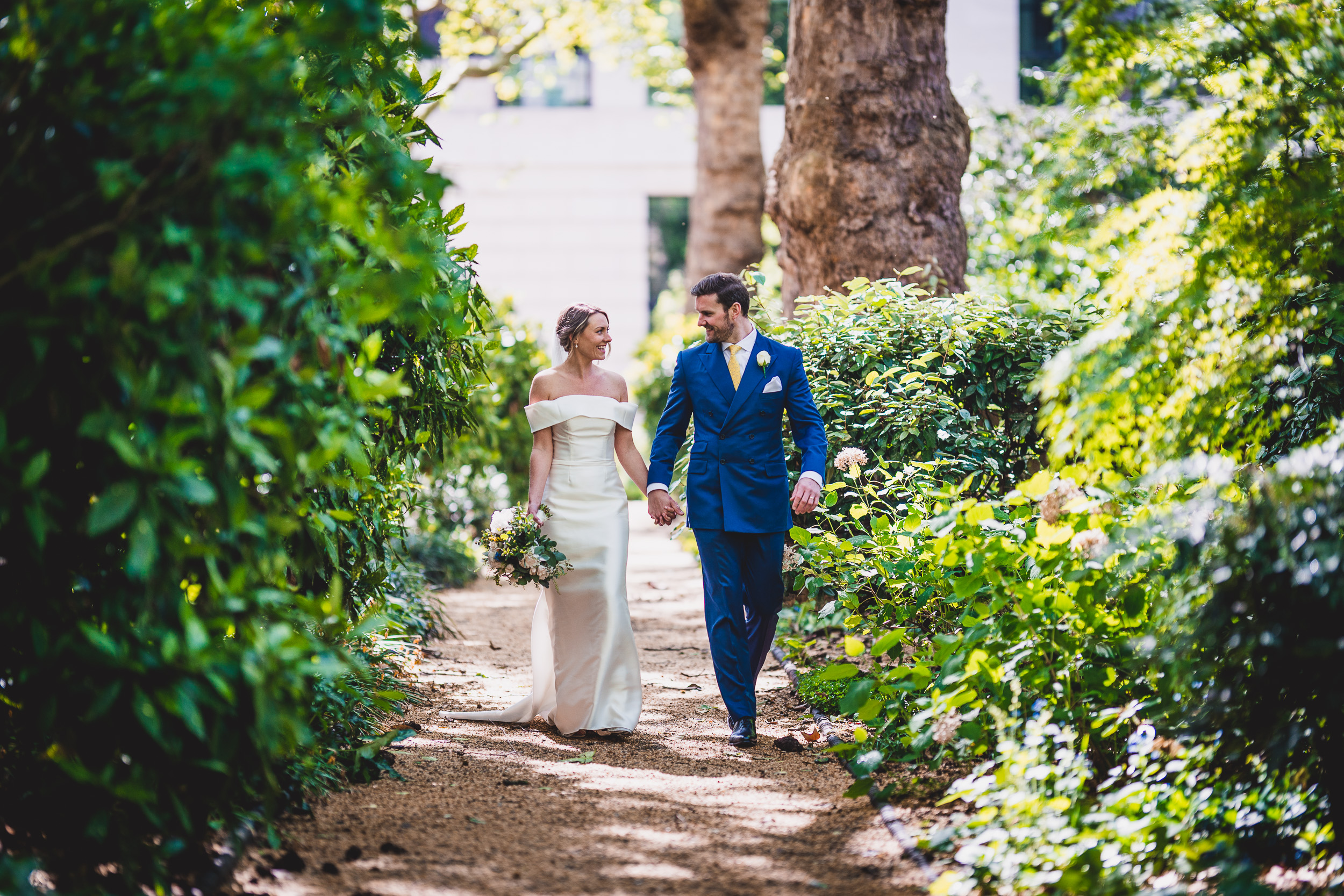 A bride and groom capturing a wedding photo in a garden.