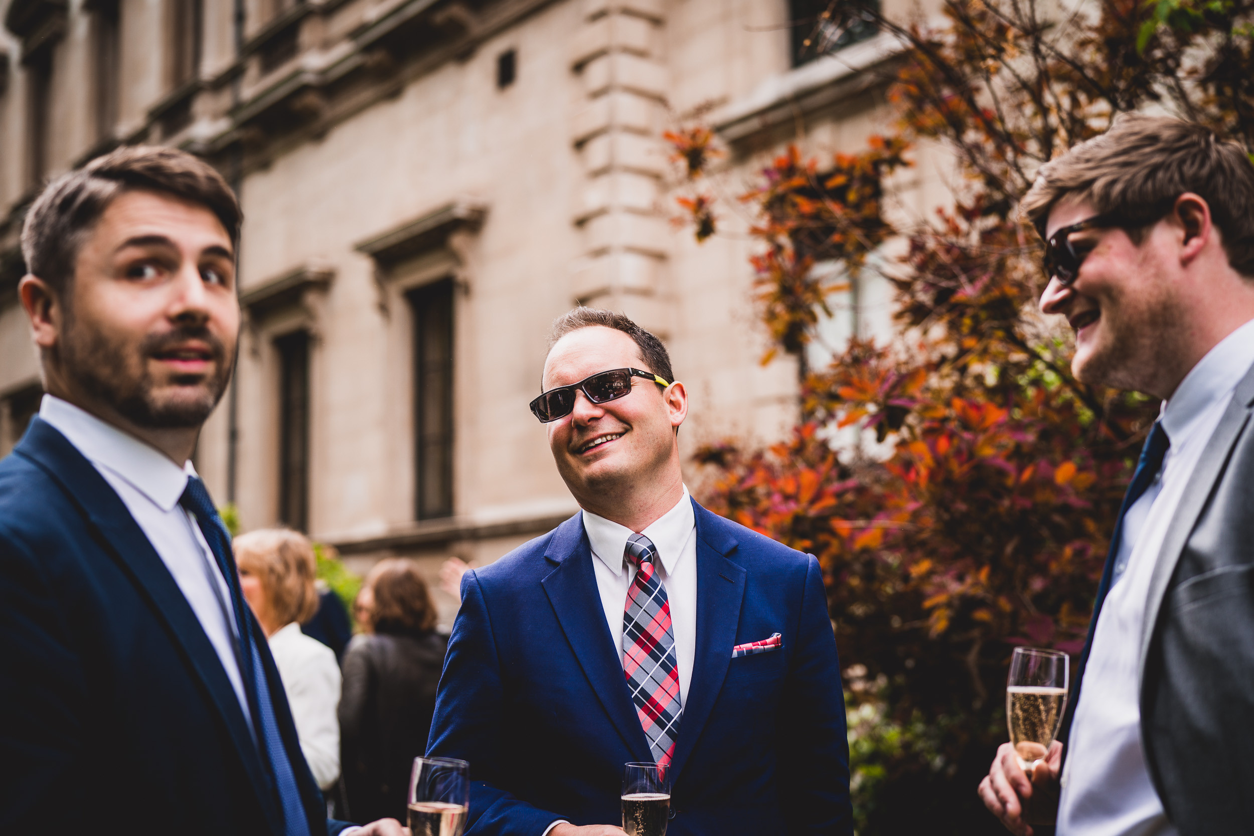 A group of men in suits and sunglasses attending a wedding photo.