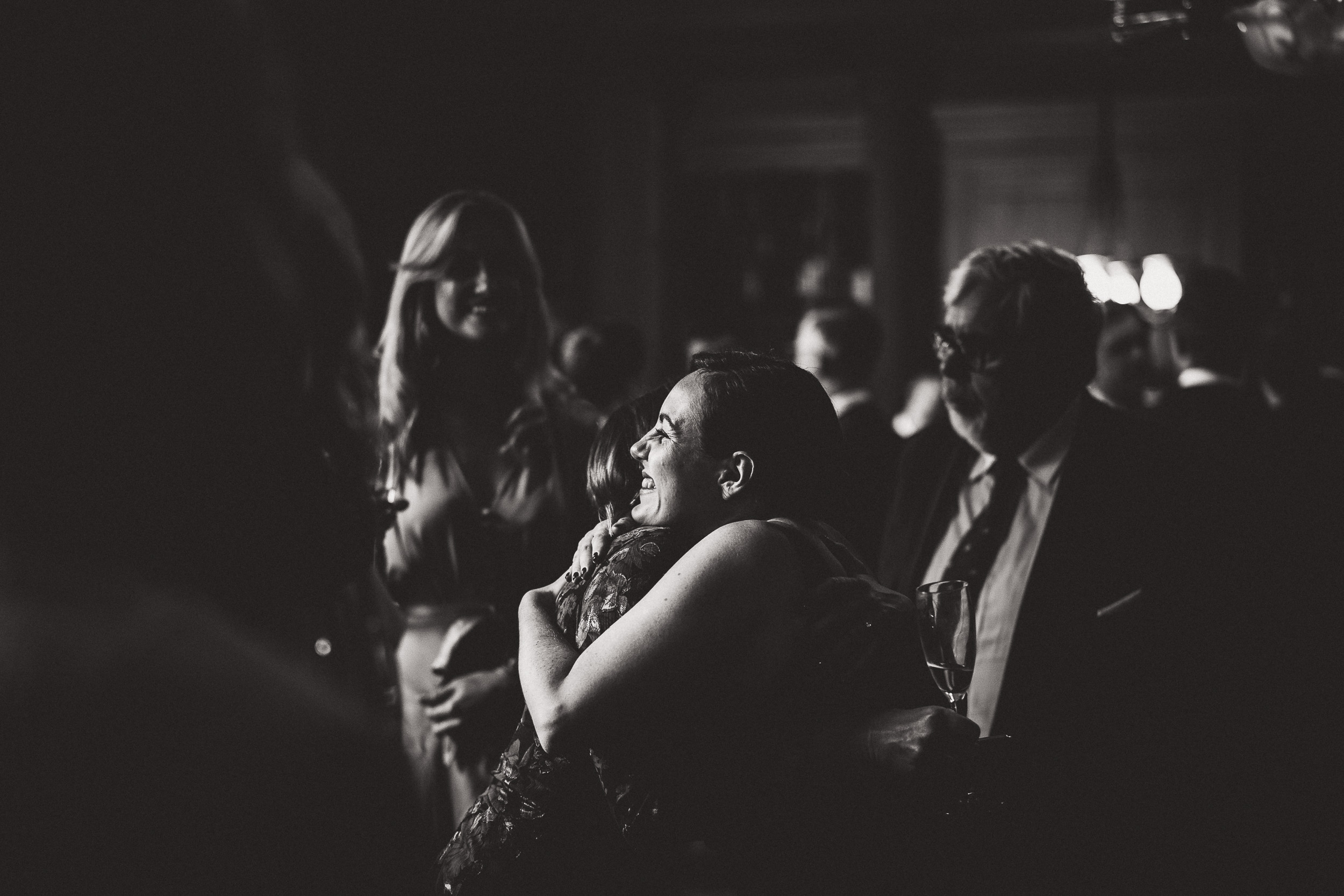 A black and white wedding photo of a bride hugging a groom.