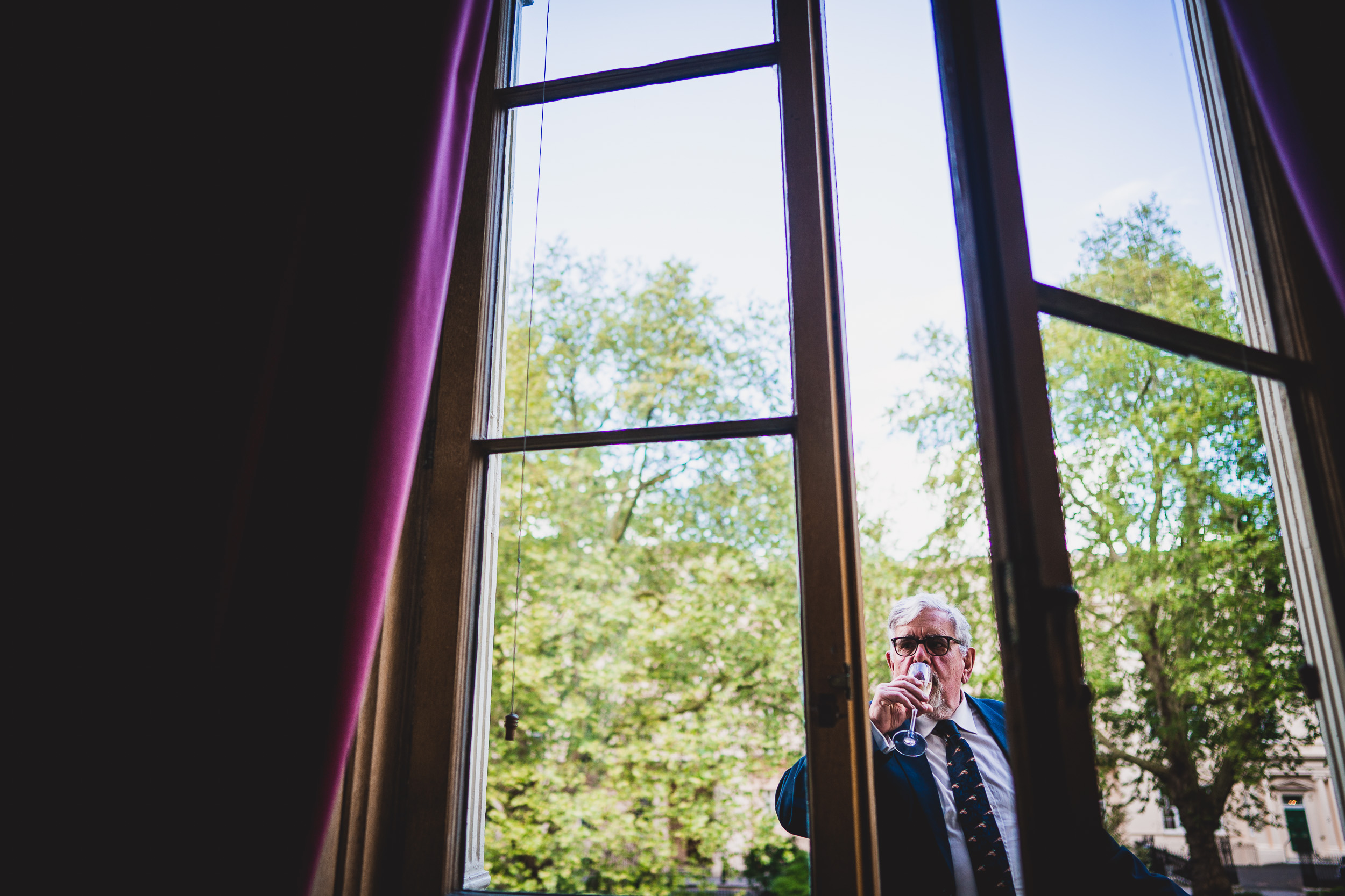 A groom in a suit looking out of a window.