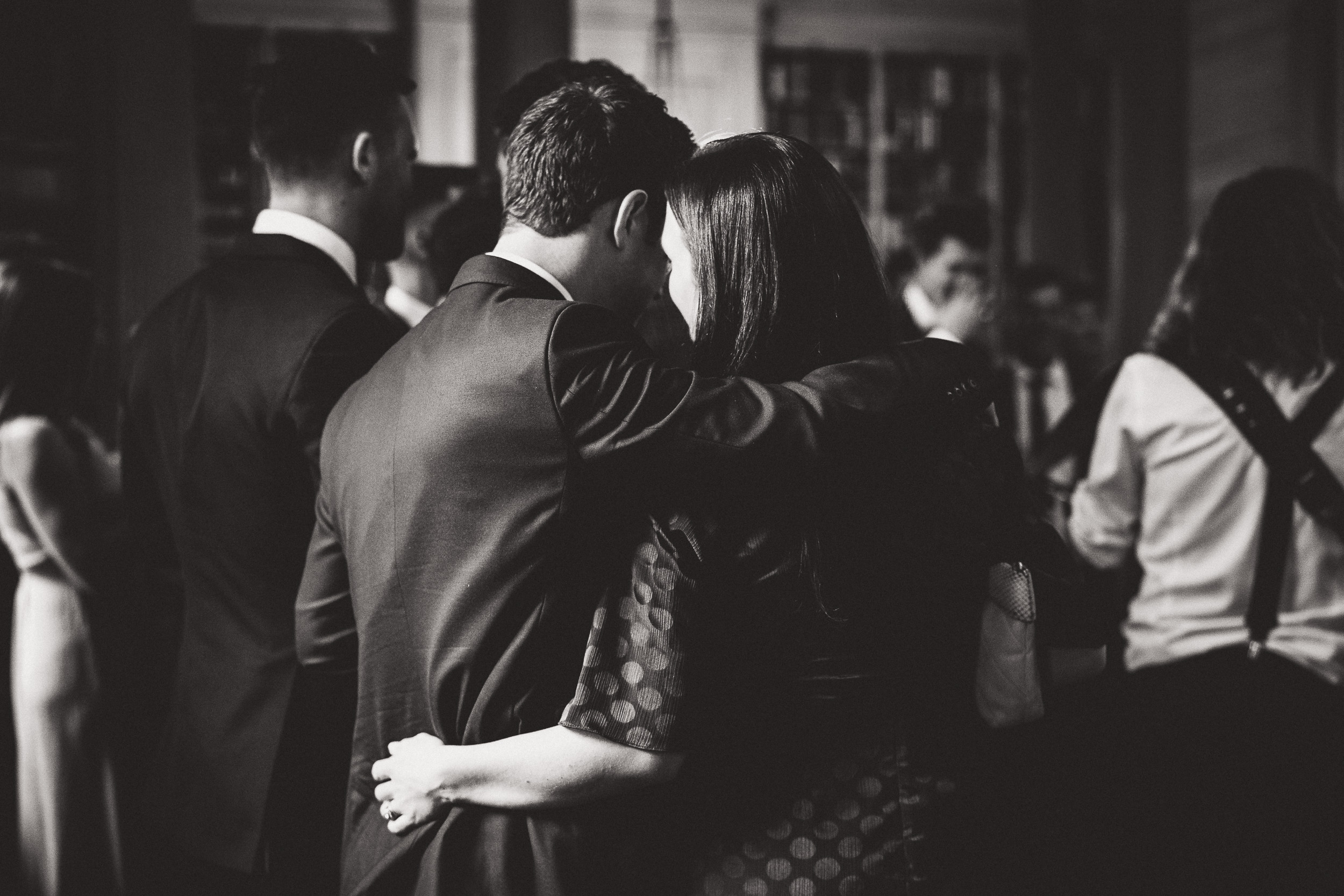 A black and white wedding photo capturing a bride and groom hugging.