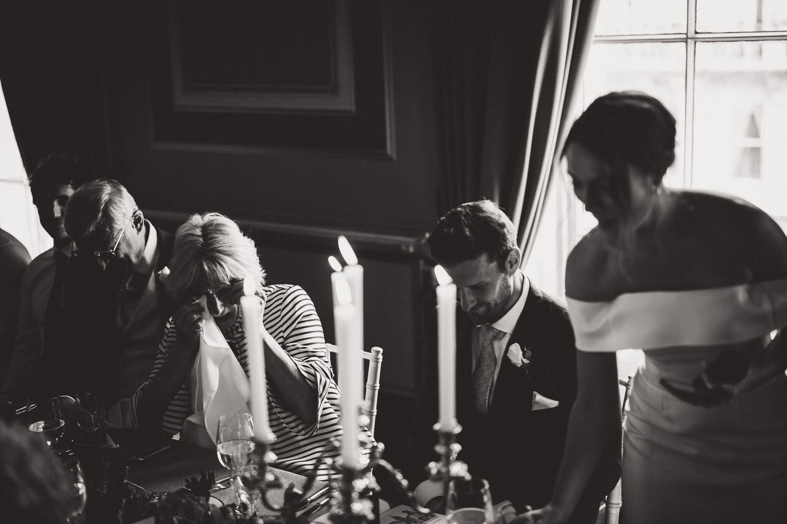 A black and white photo of a group of people at a wedding table.