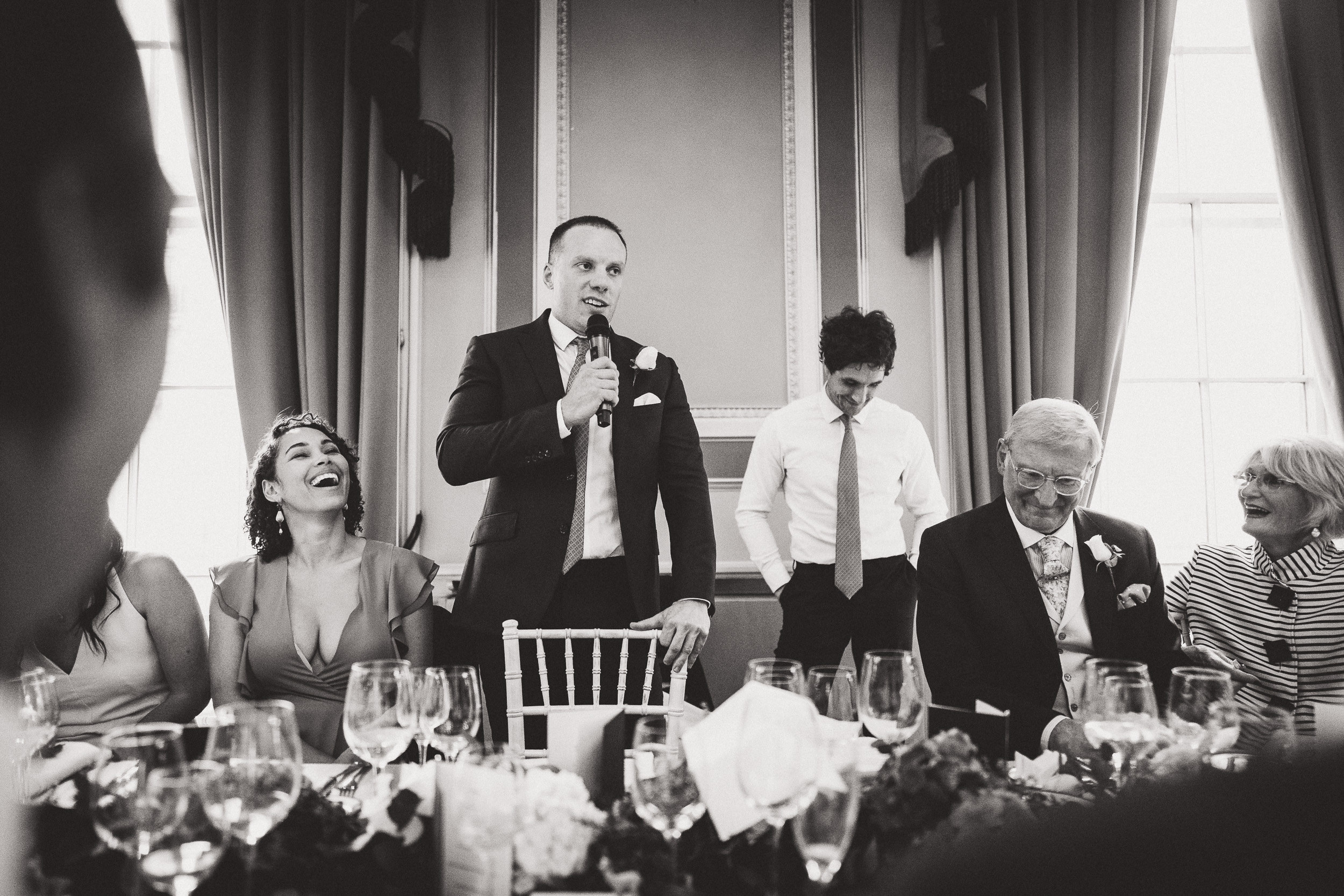 A wedding photo of a groom giving a speech.