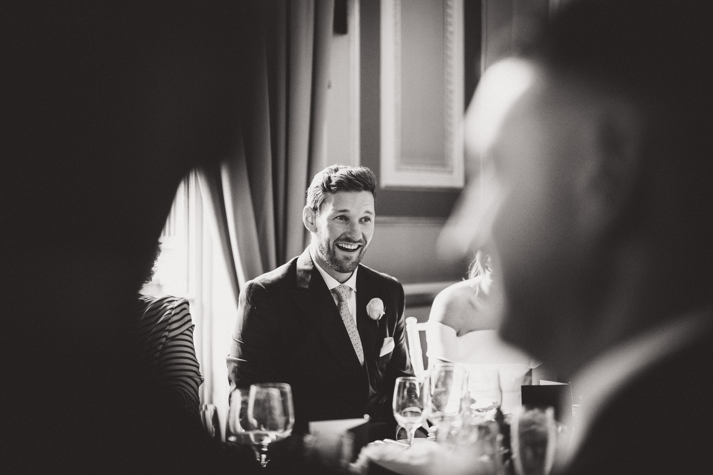 A wedding photo capturing a joyful moment as the groom bursts into laughter.