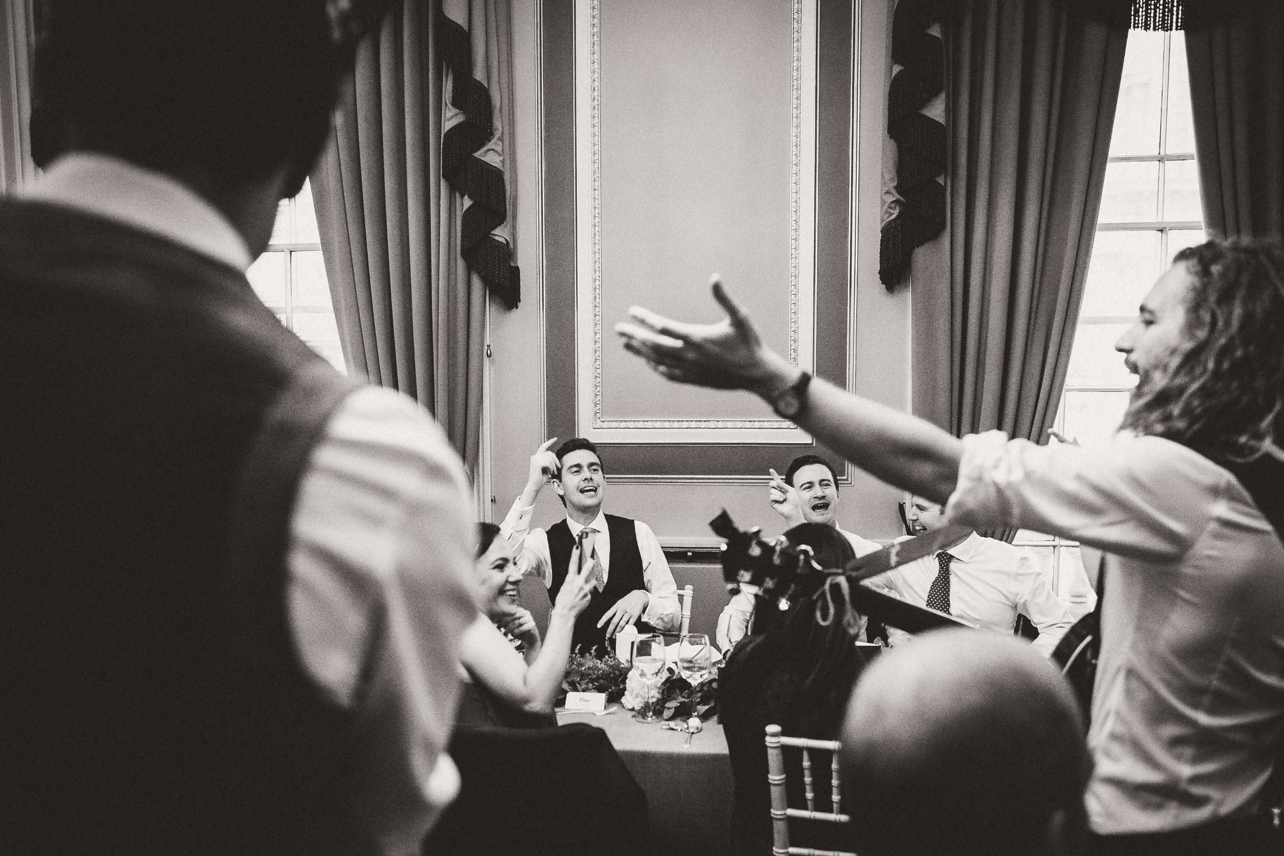 A black and white photo capturing a group of people including the groom and bride at their wedding.