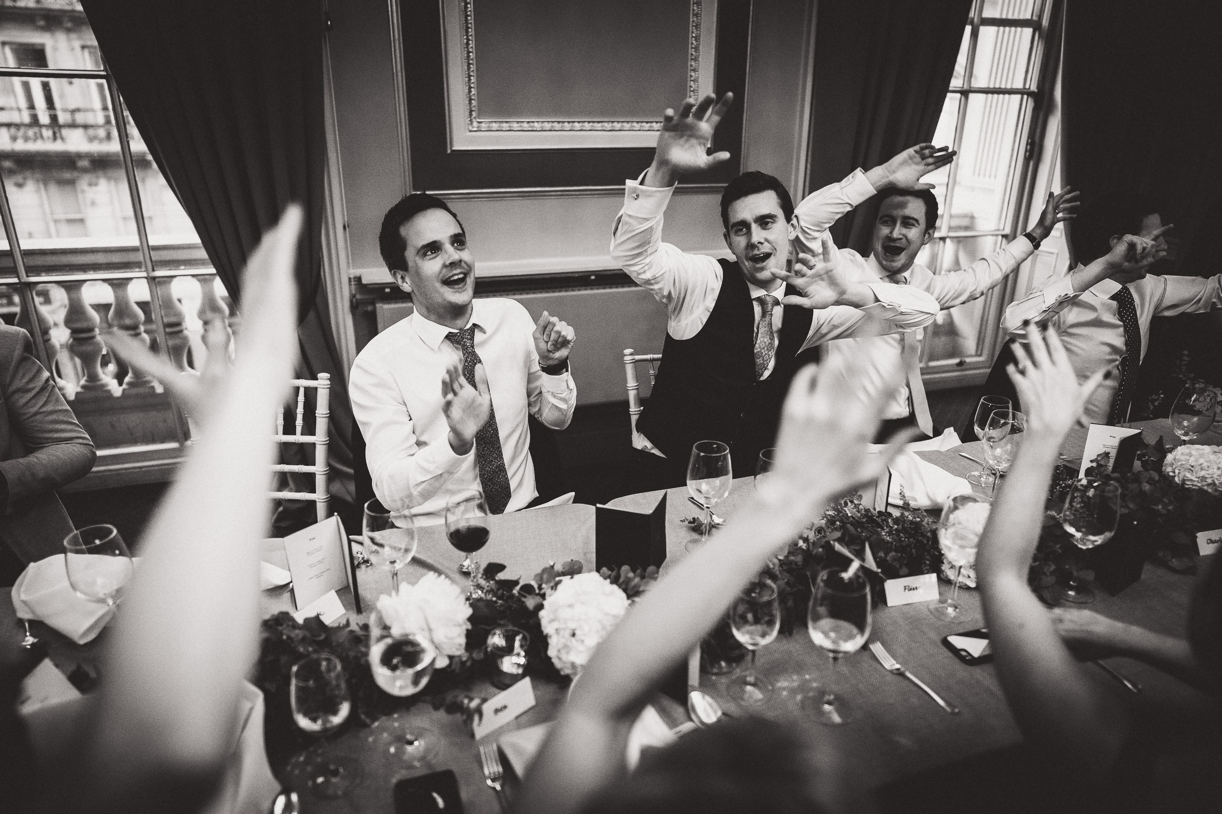 A black and white photo of a group of people at a wedding, including the bride and groom.