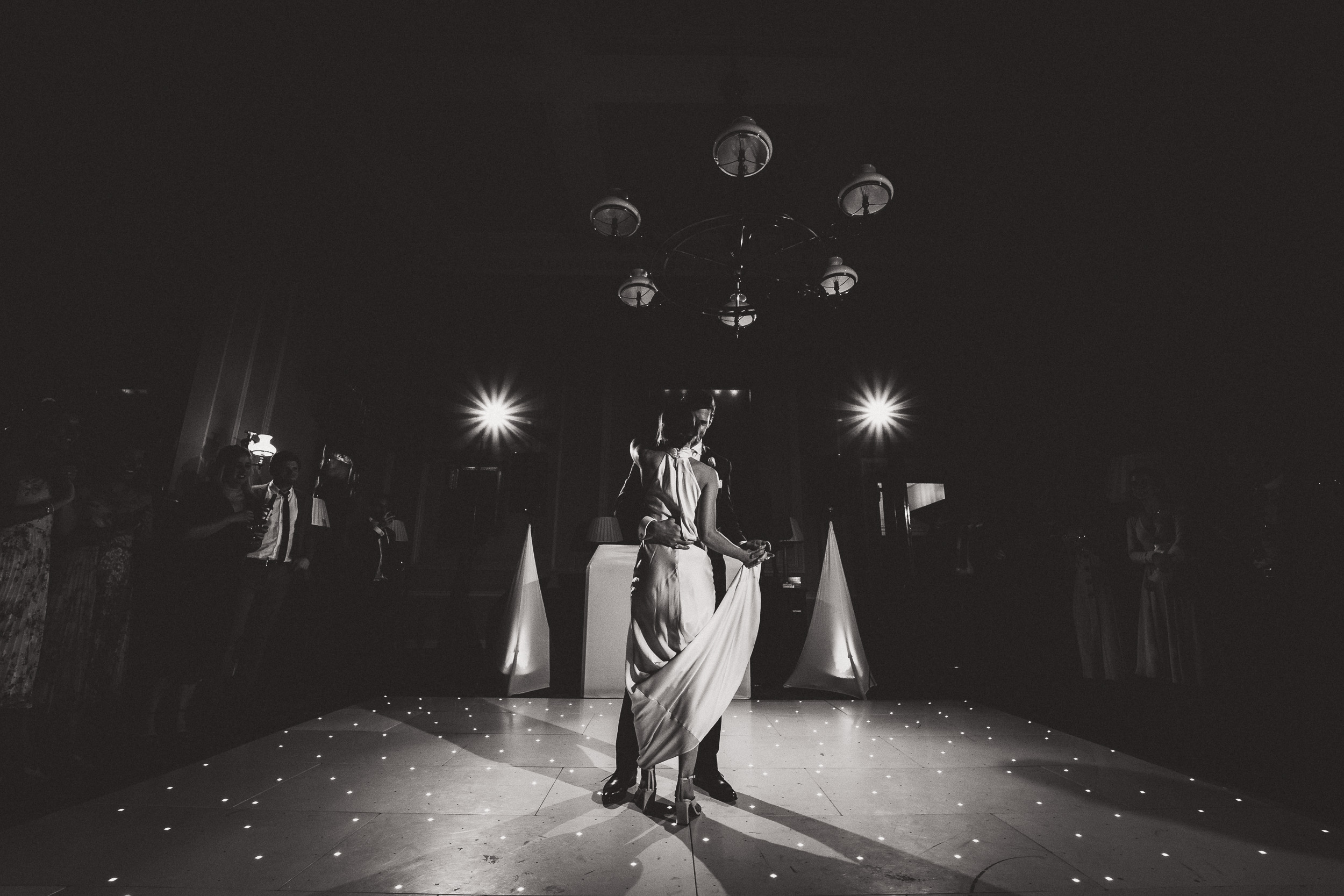 A wedding photo captures a black and white moment of a bride and groom dancing on the dance floor.