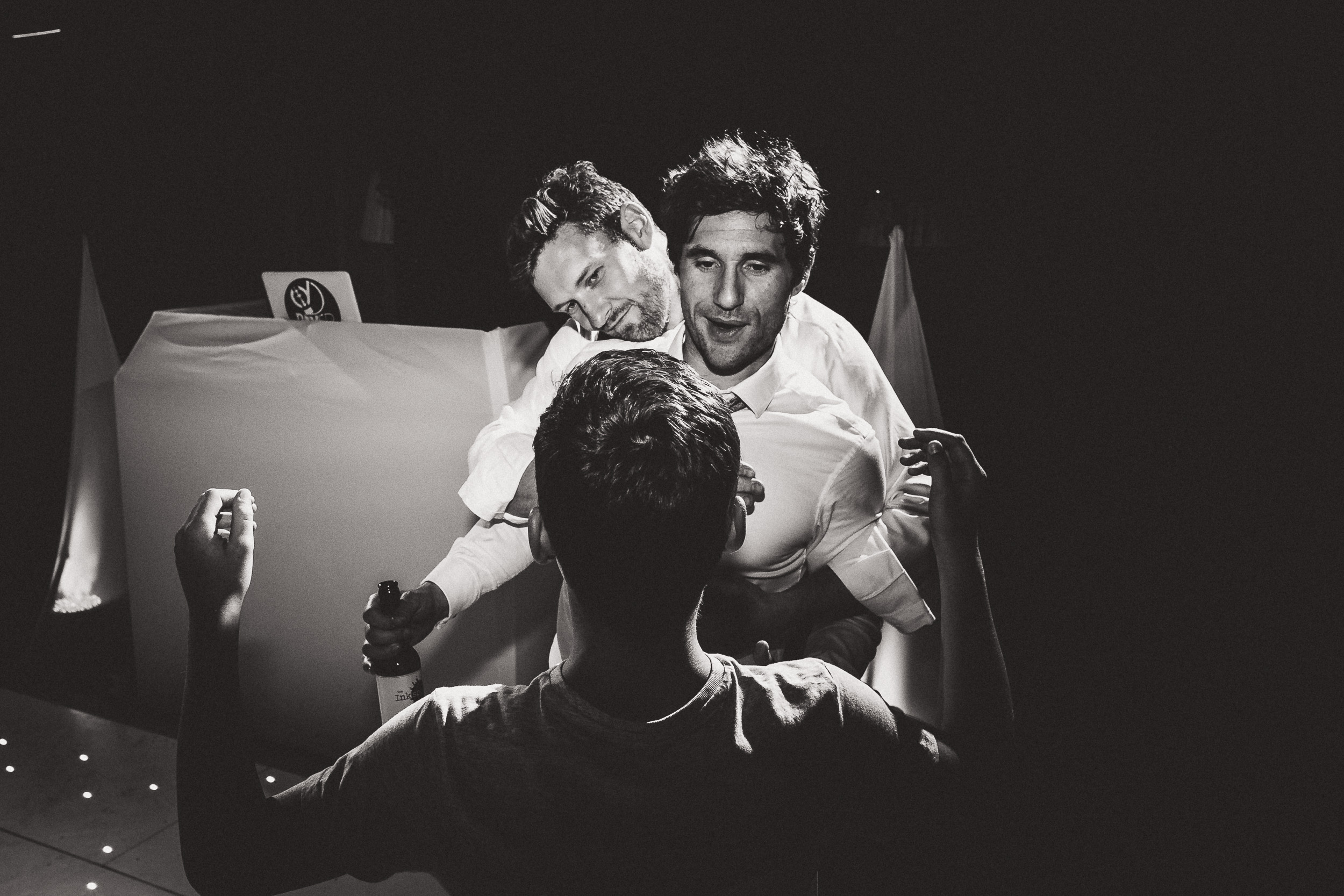 A black and white wedding photo of a bride and groom in a dark room.