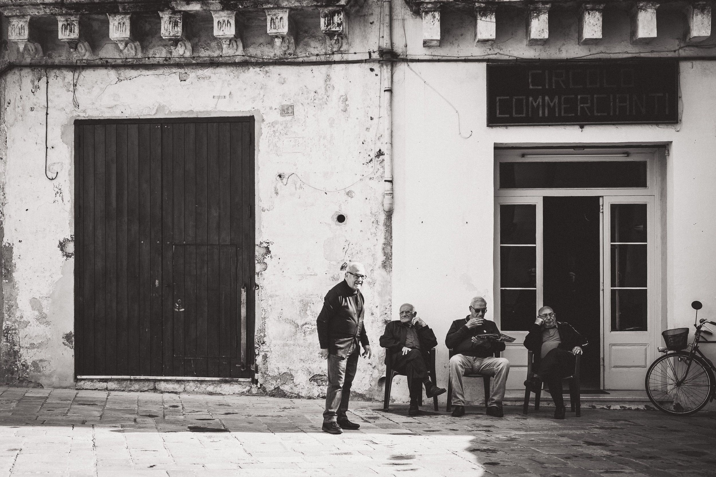 A black and white wedding photo of a group of people in front of a building, captured by the wedding photographer.