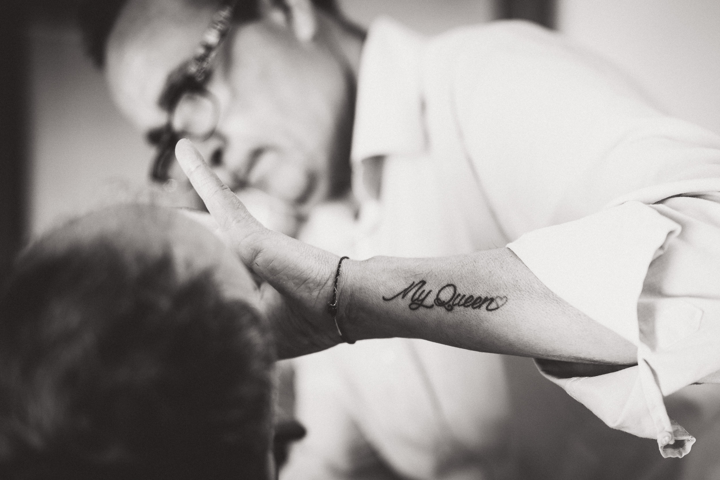 A groom is getting a tattoo on his arm before his wedding.