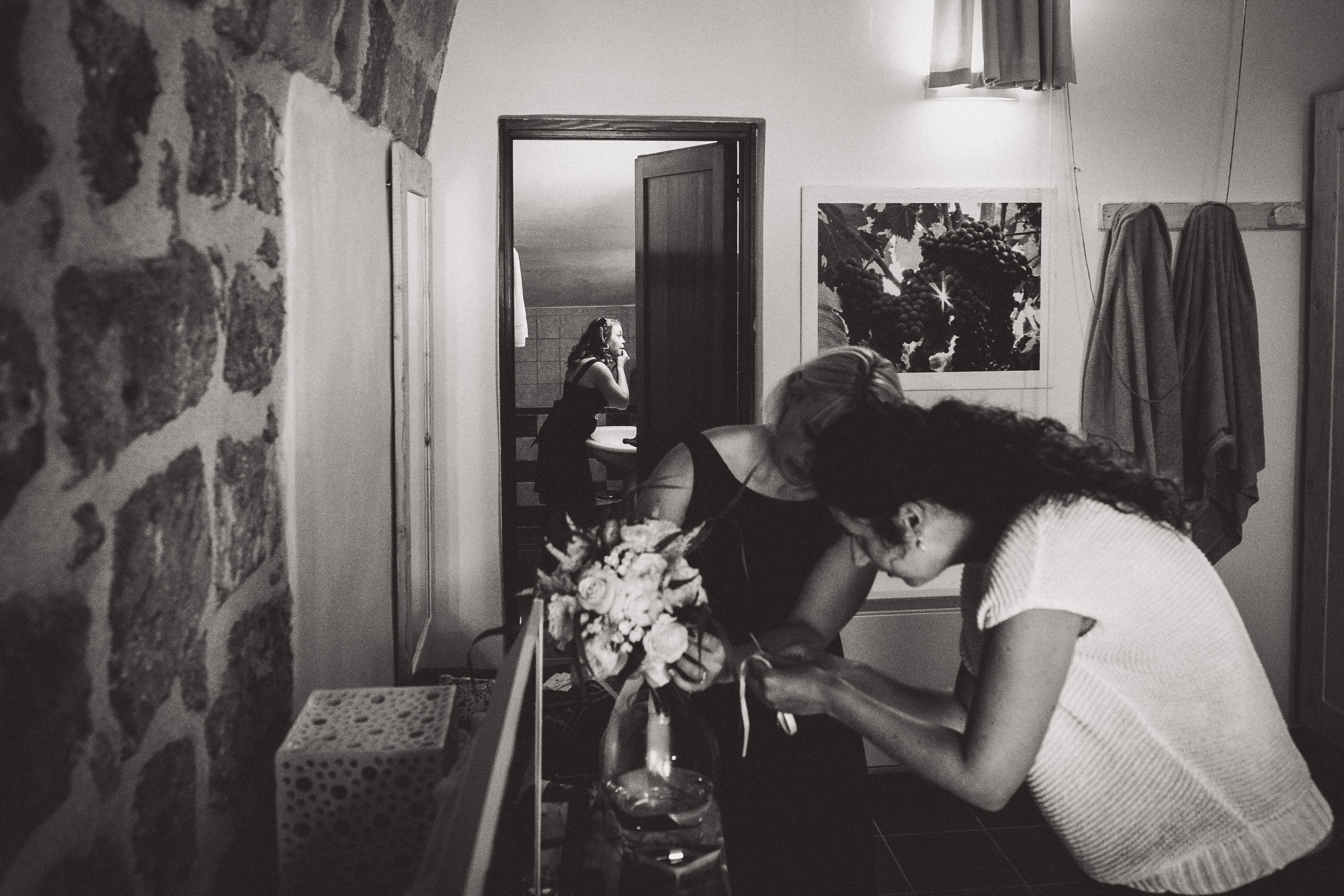 A bride is arranging flowers in front of a mirror.