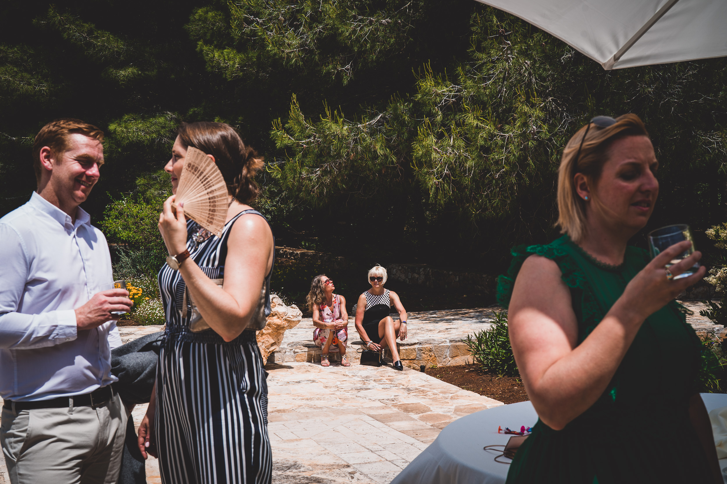 A wedding photographer captures the bride and groom together with a group of people at a wedding.