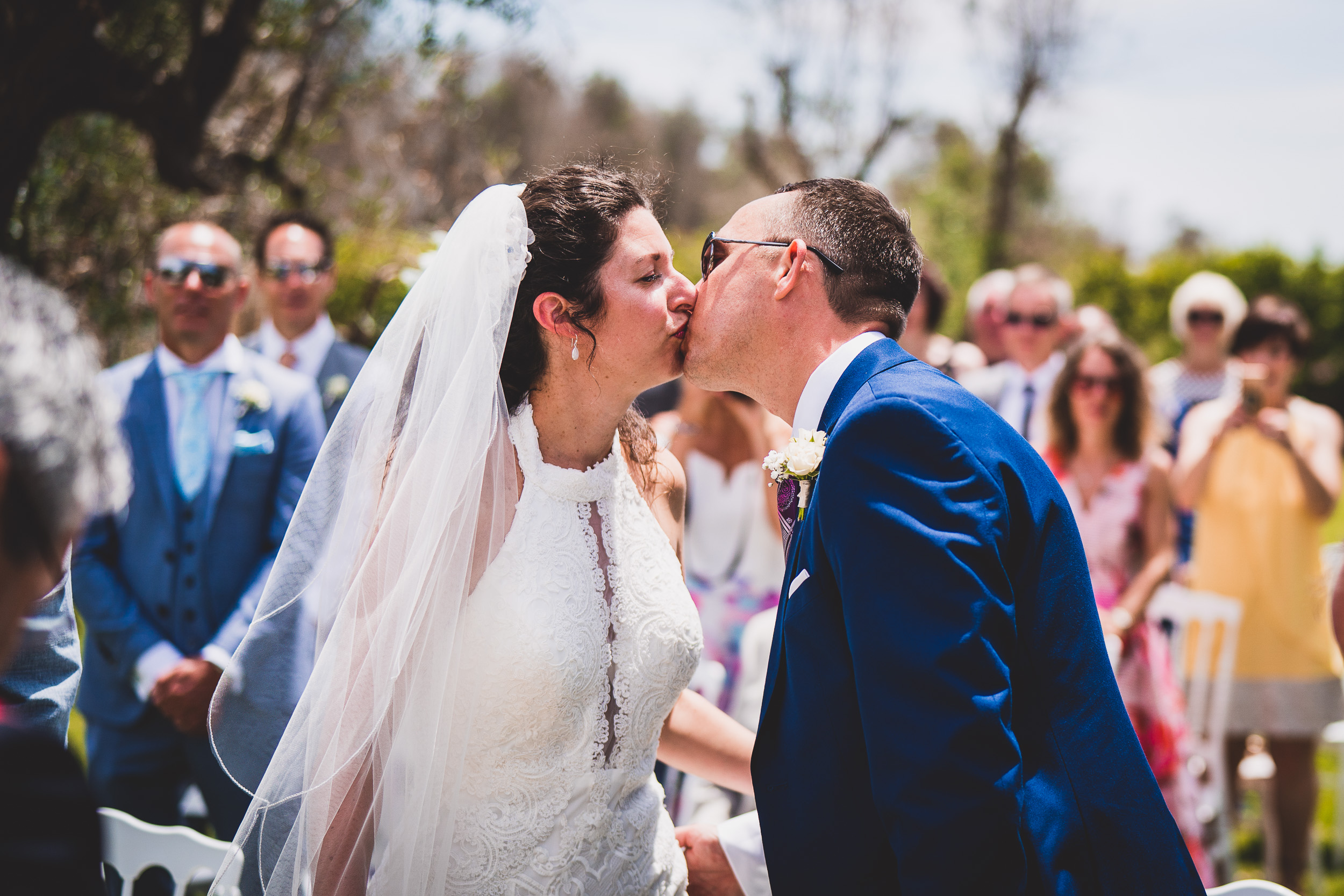 The groom kisses the bride while the wedding photographer captures the moment.