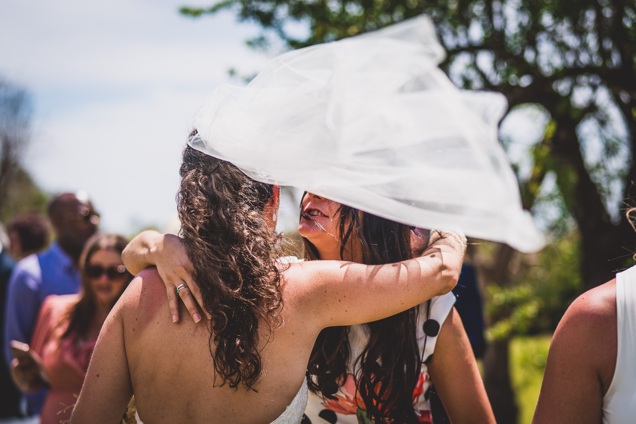 A wedding photographer capturing a heartwarming wedding photo of two brides embracing each other.