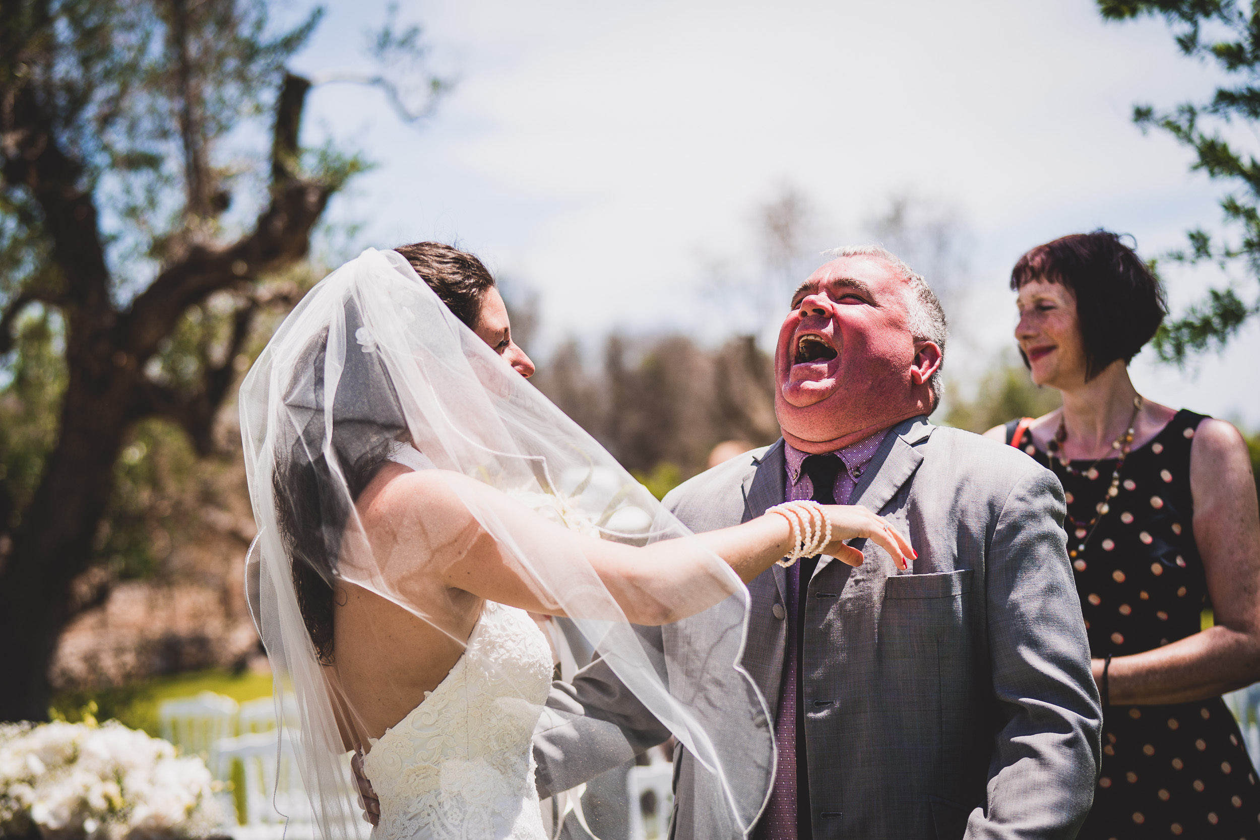 A groom and wedding photographer capture the bride's laughter during her wedding ceremony.