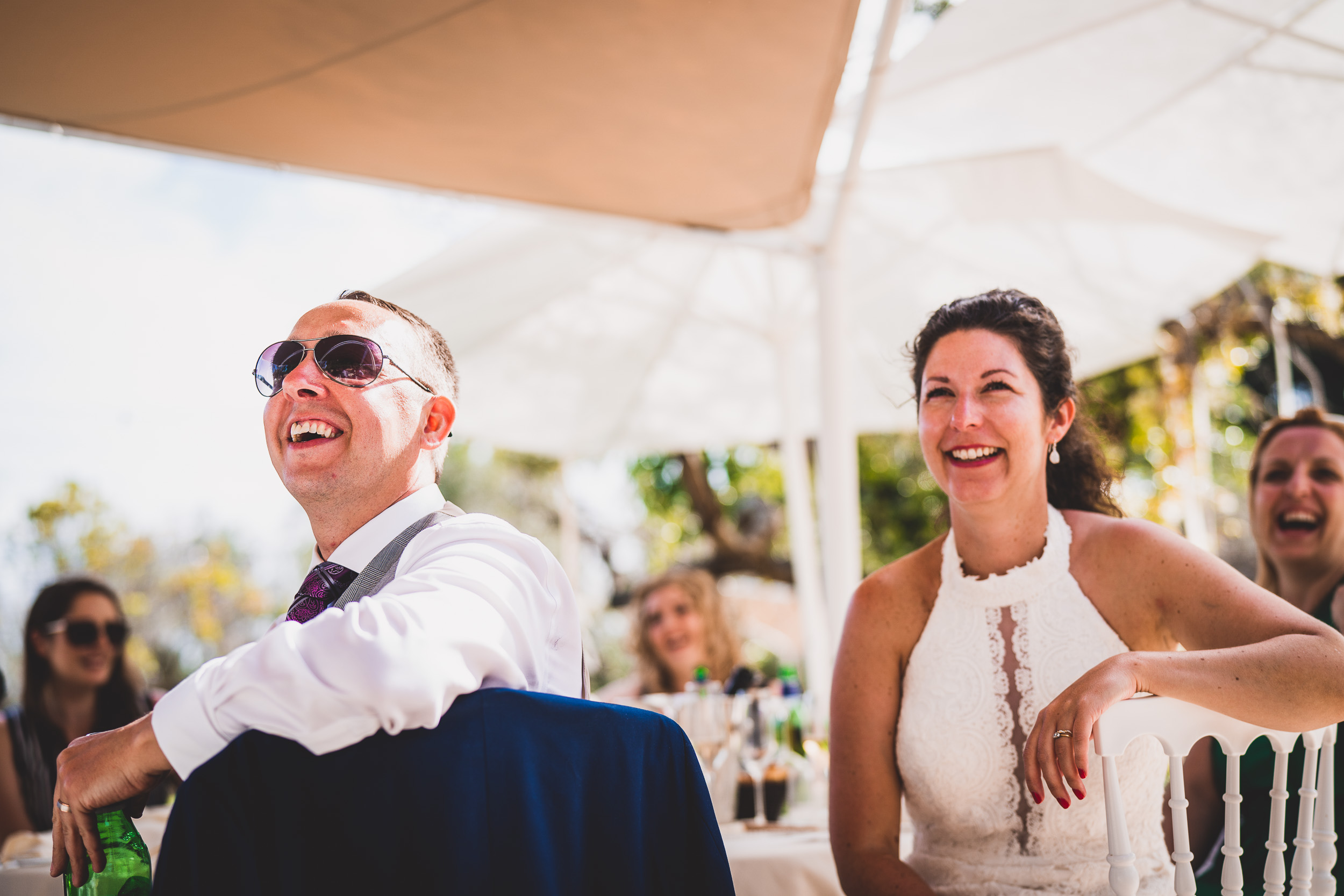 A wedding photo capturing the joyful laughter of a bride and groom.