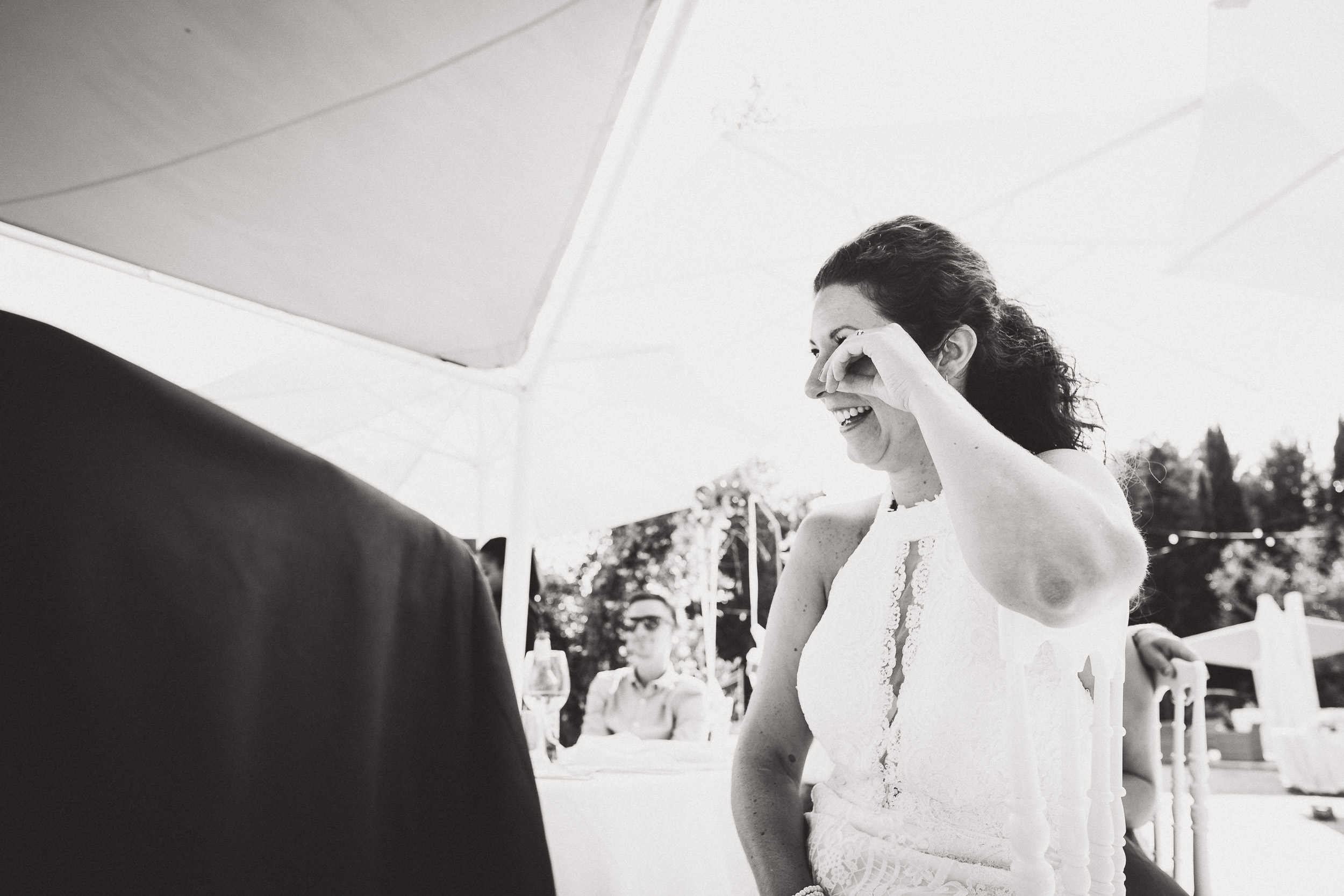 A bride is wiping her eyes with her hand in a wedding photo.