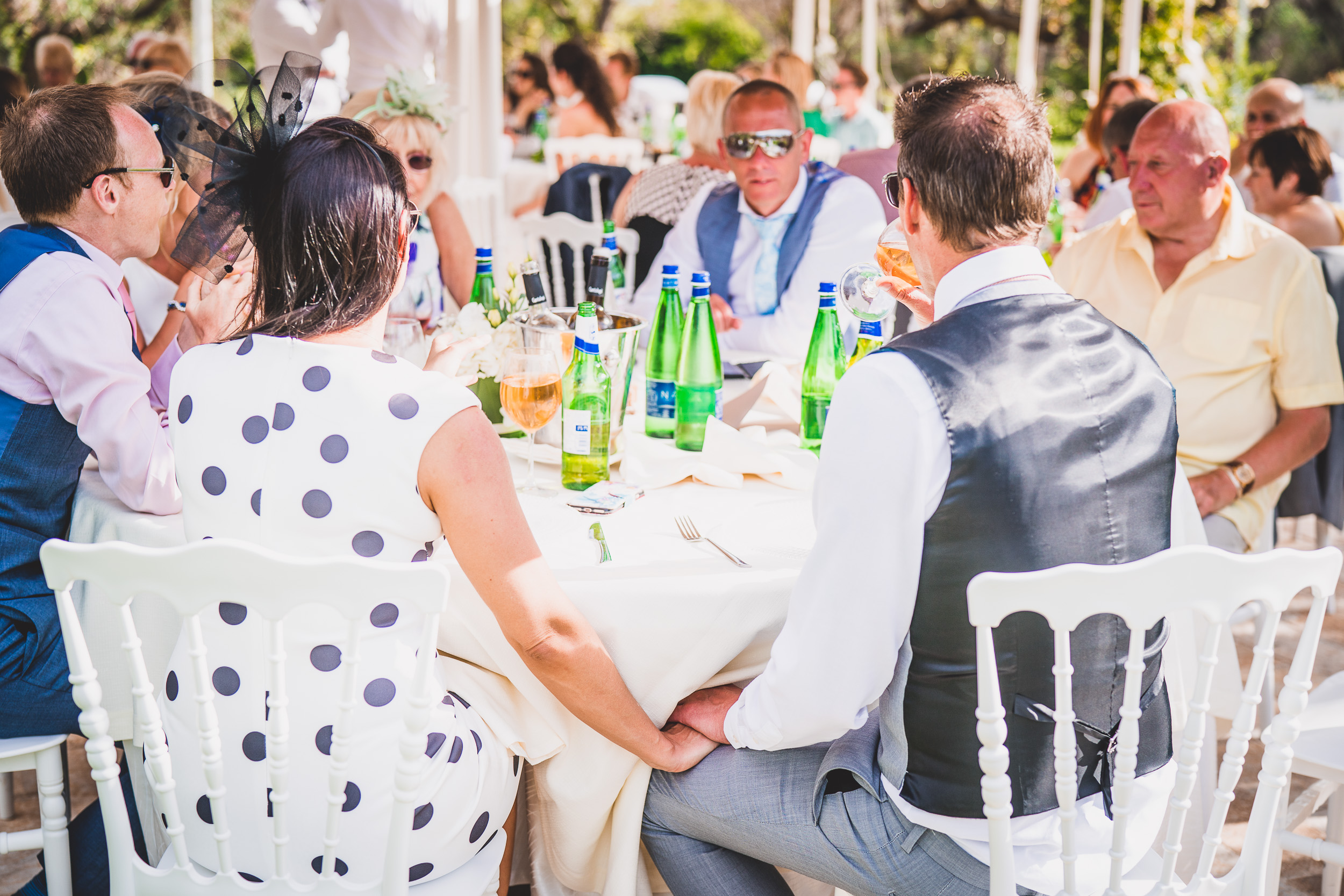 A wedding group gathered around a table capturing moments with the photographer.