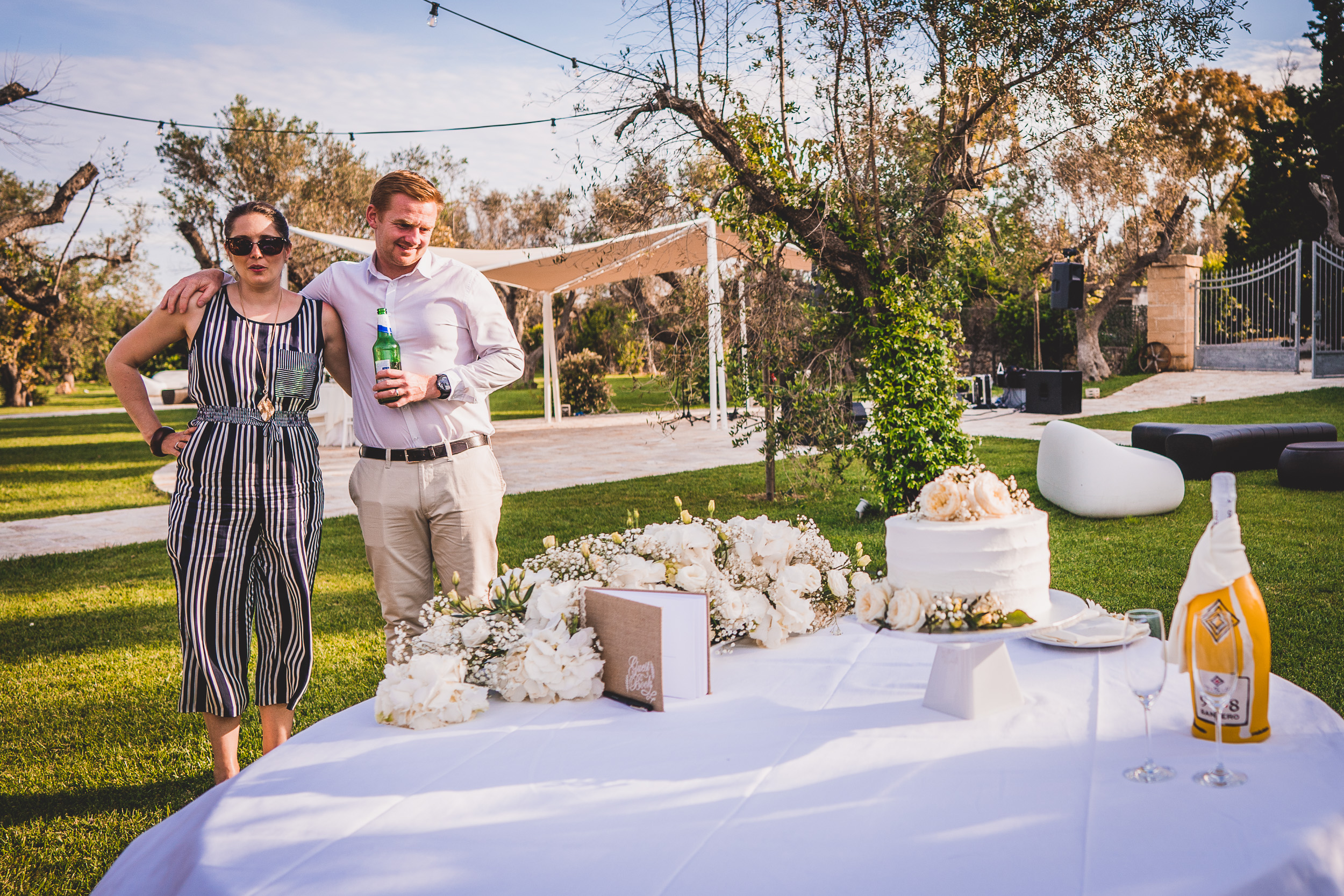 A wedding photographer capturing a bride and groom next to a table with a cake.