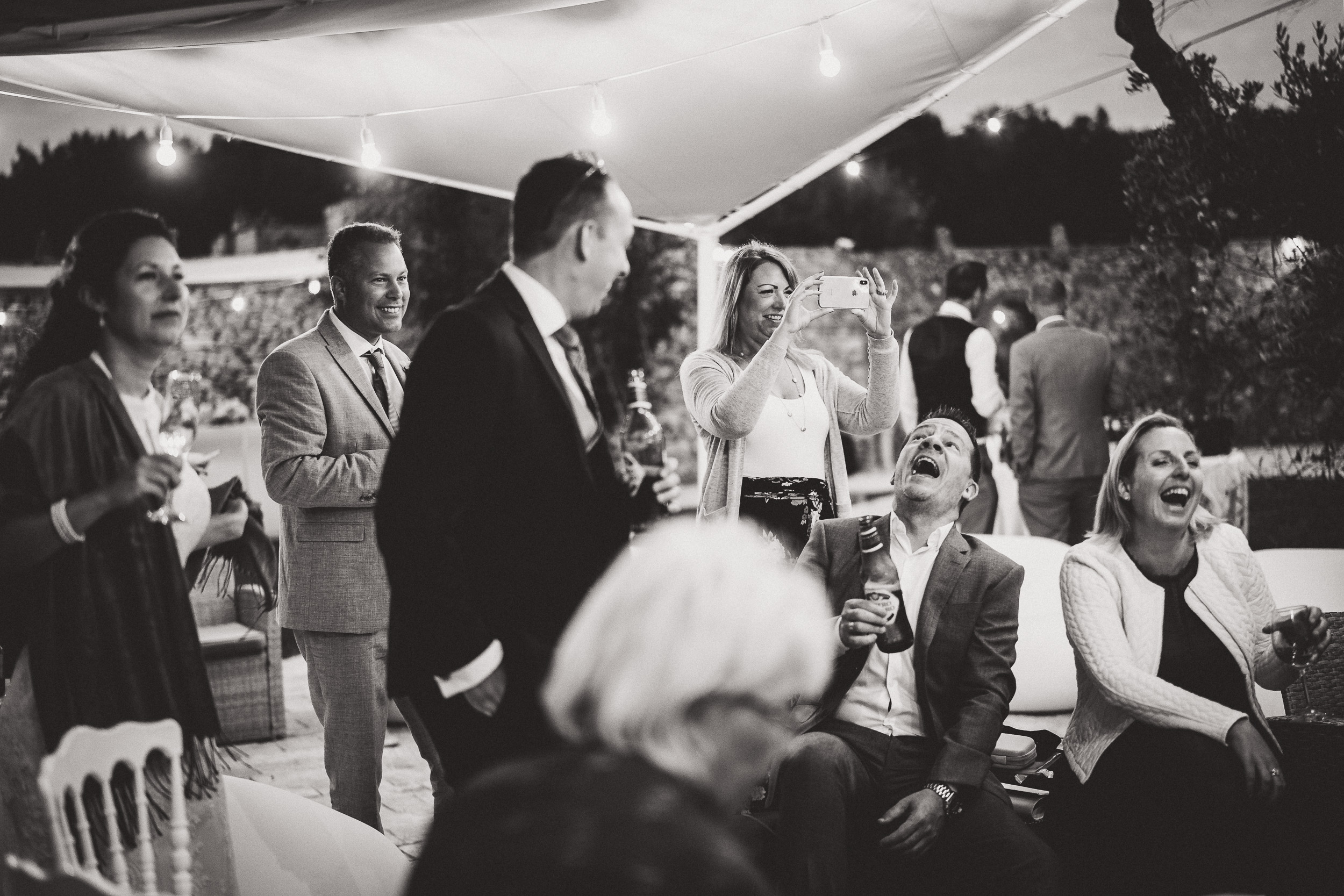 A black and white wedding photo capturing a group of people at the party.